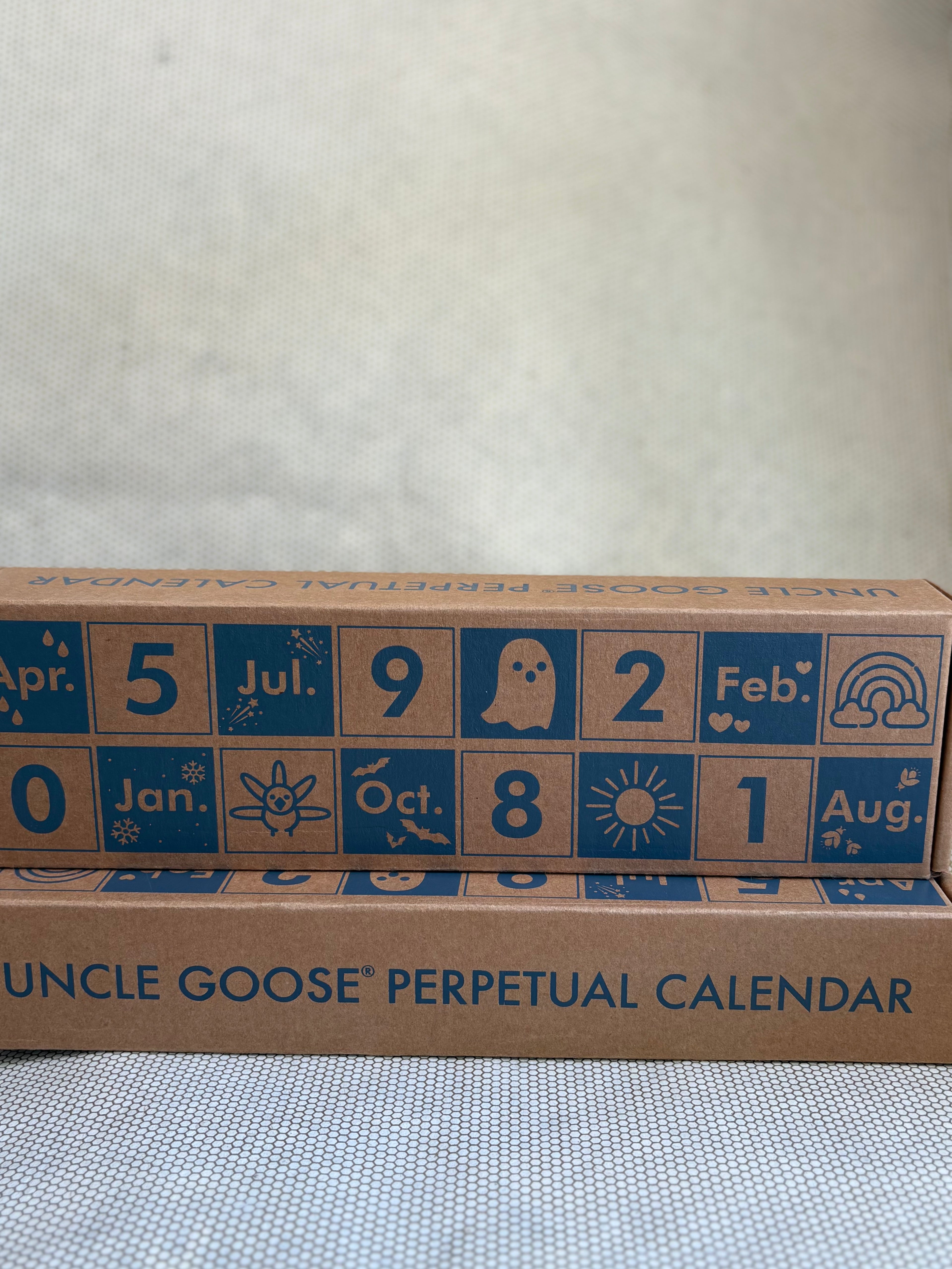 Uncle Goose perpetual calendar with blue text and symbols on a cardboard box.