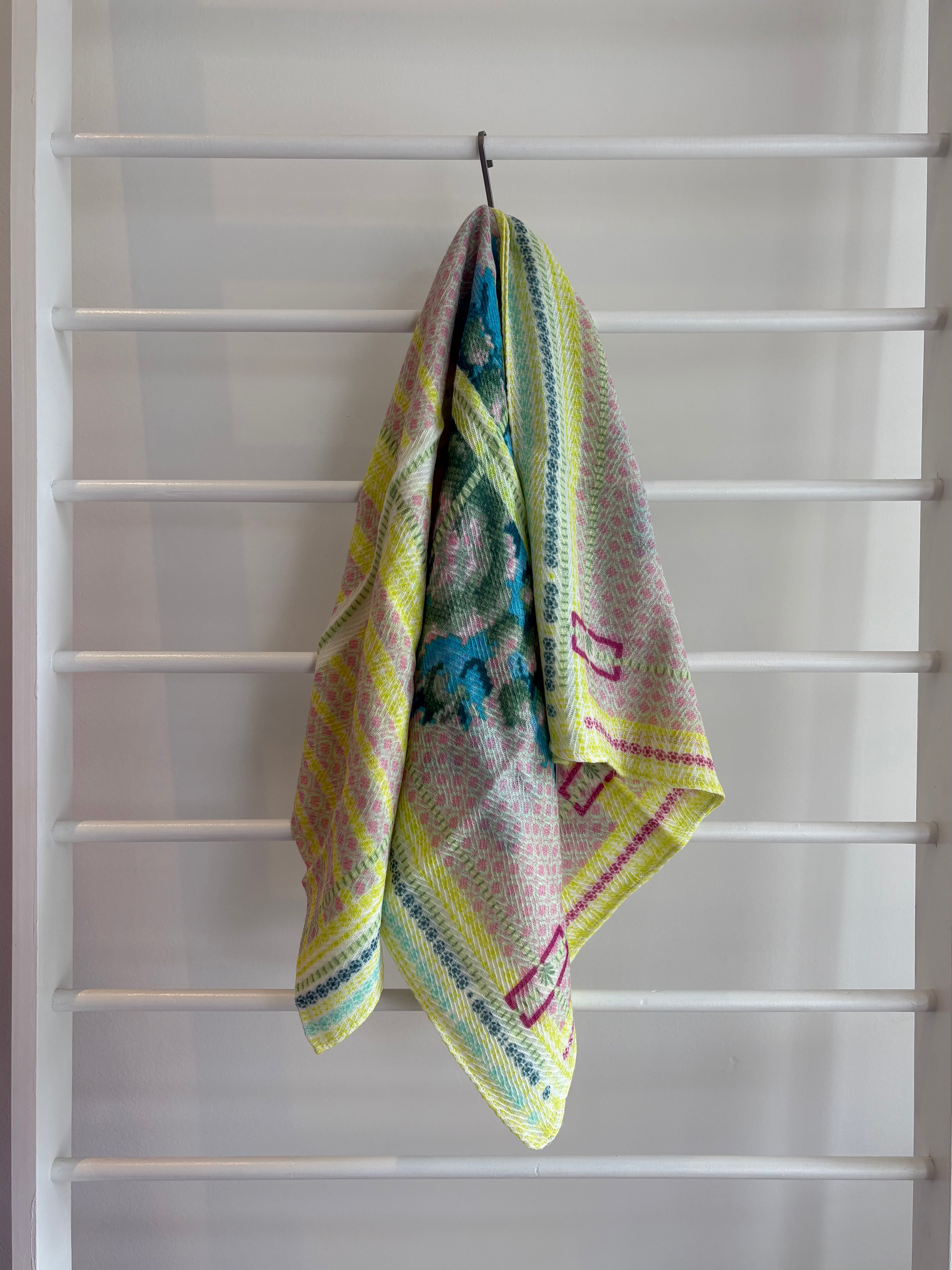 floral brightly colored scarf on rack pink, blue, green, yellow design. 