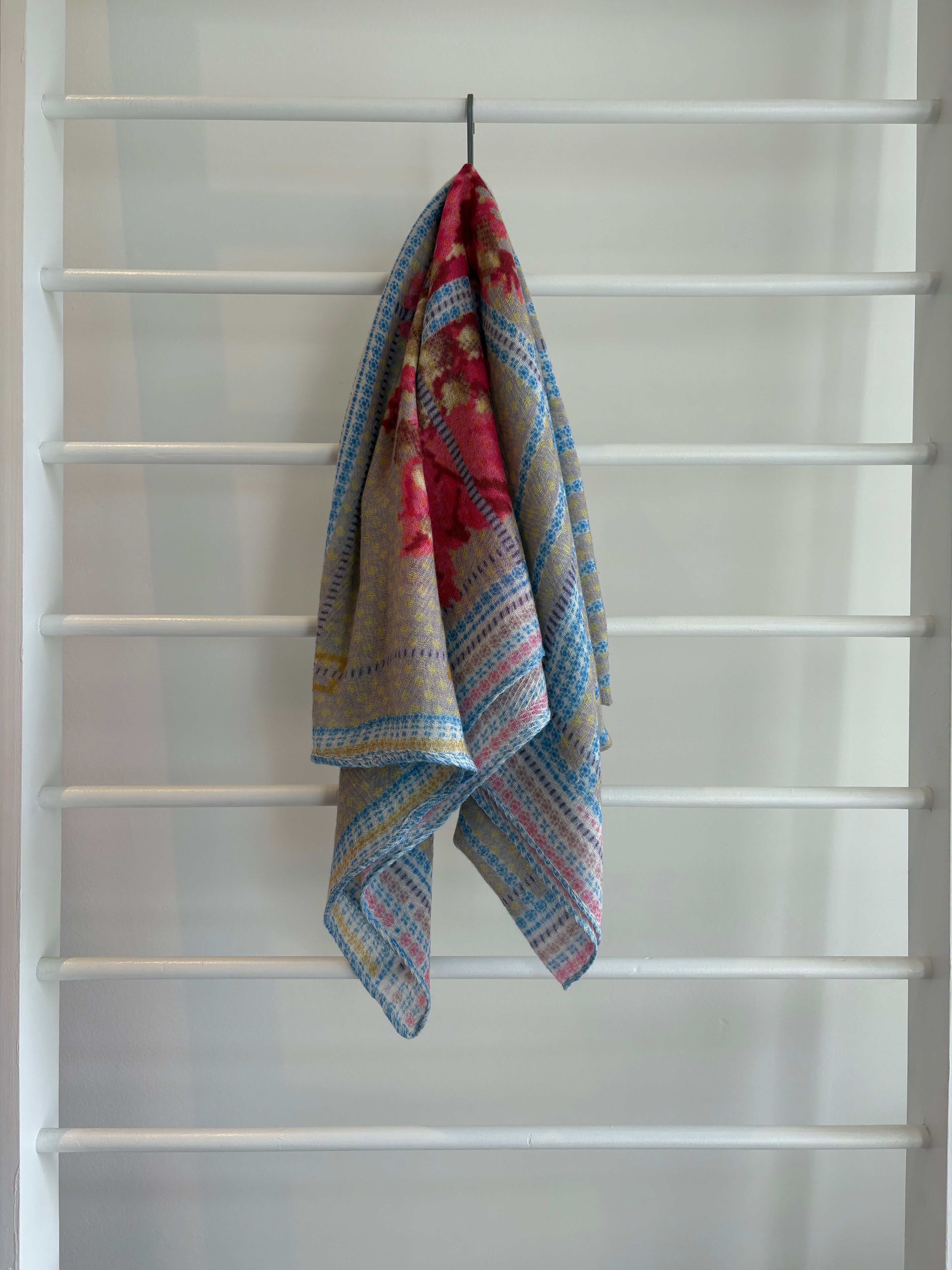 floral brightly colored scarf on rack pink, blue, red, yellow brown design. 