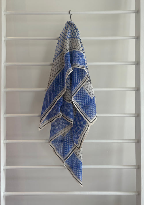 hanging lightweight wool scarf on rack with blue, black, and white design.