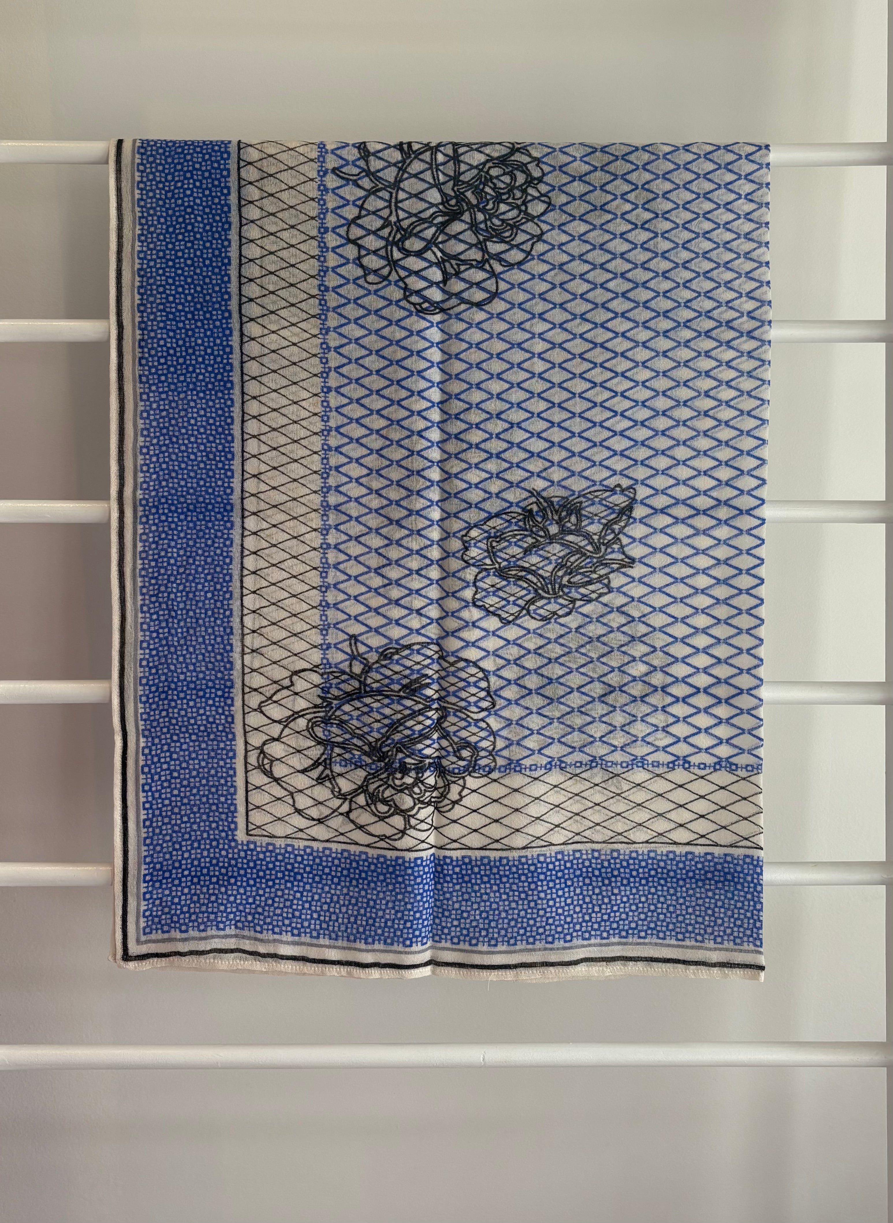 hanging lightweight wool scarf on rack with blue, black, and white design.