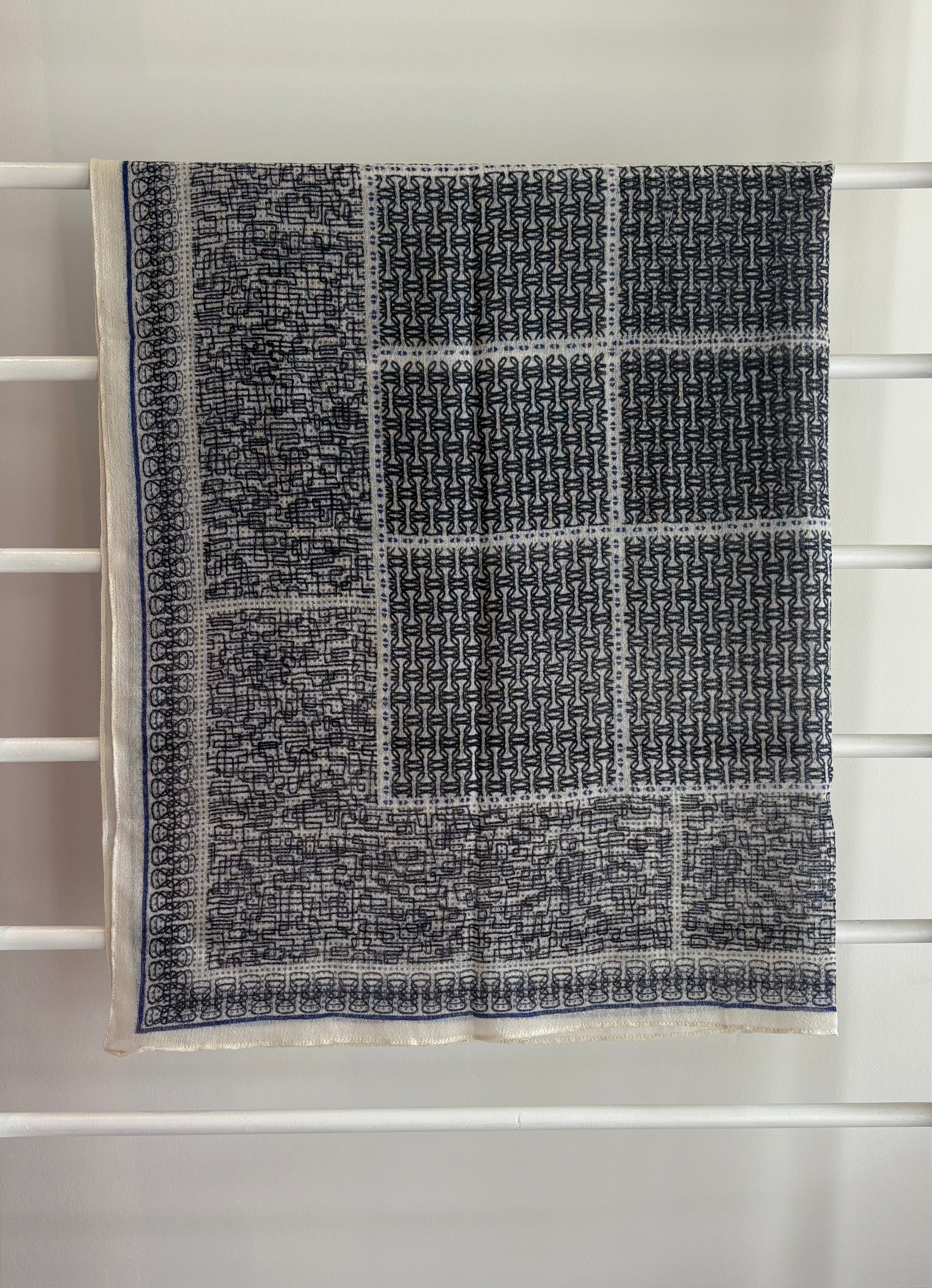 hanging lightweight wool scarf on rack with blue, and black design.