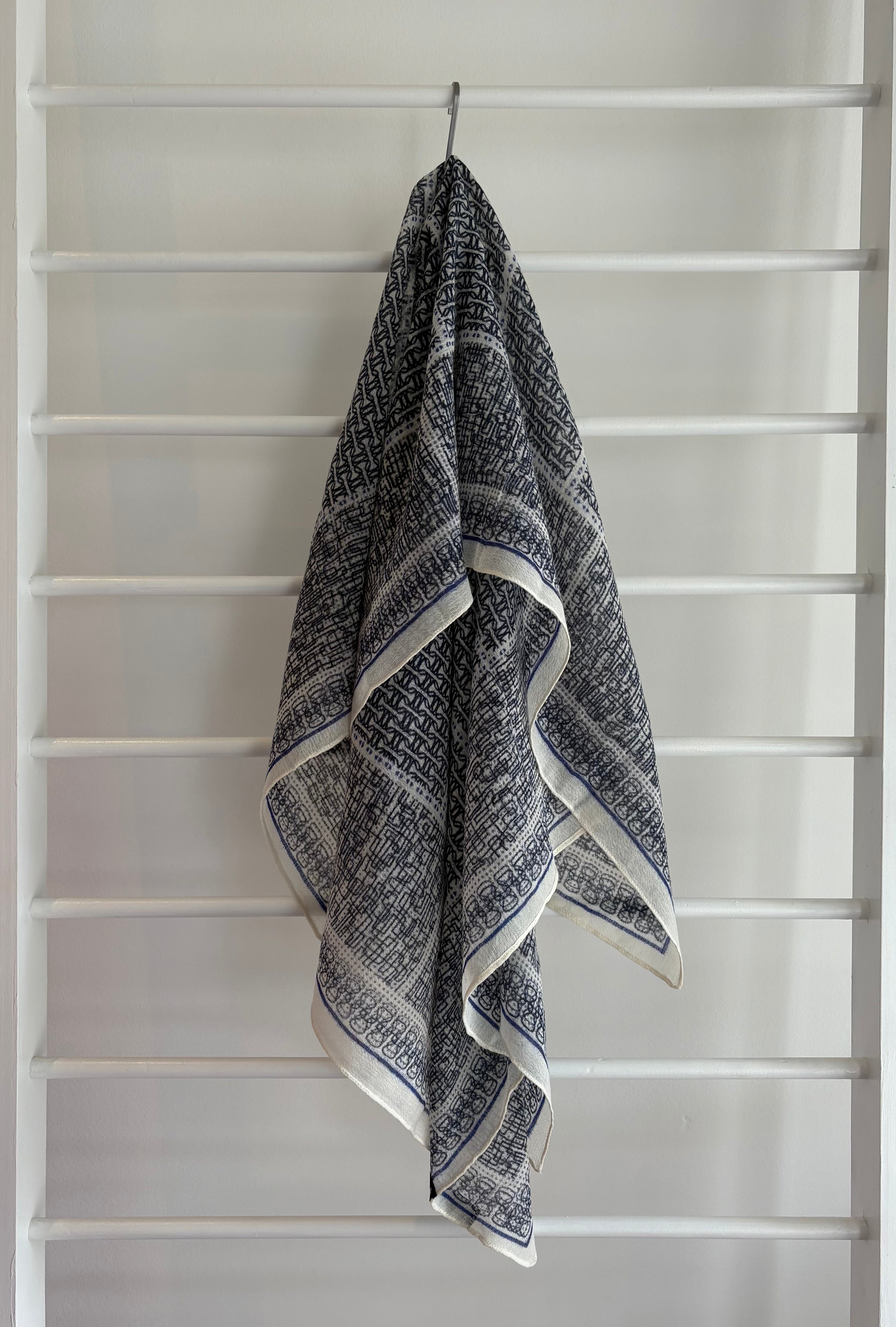 hanging lightweight wool scarf on rack with blue, and black design.