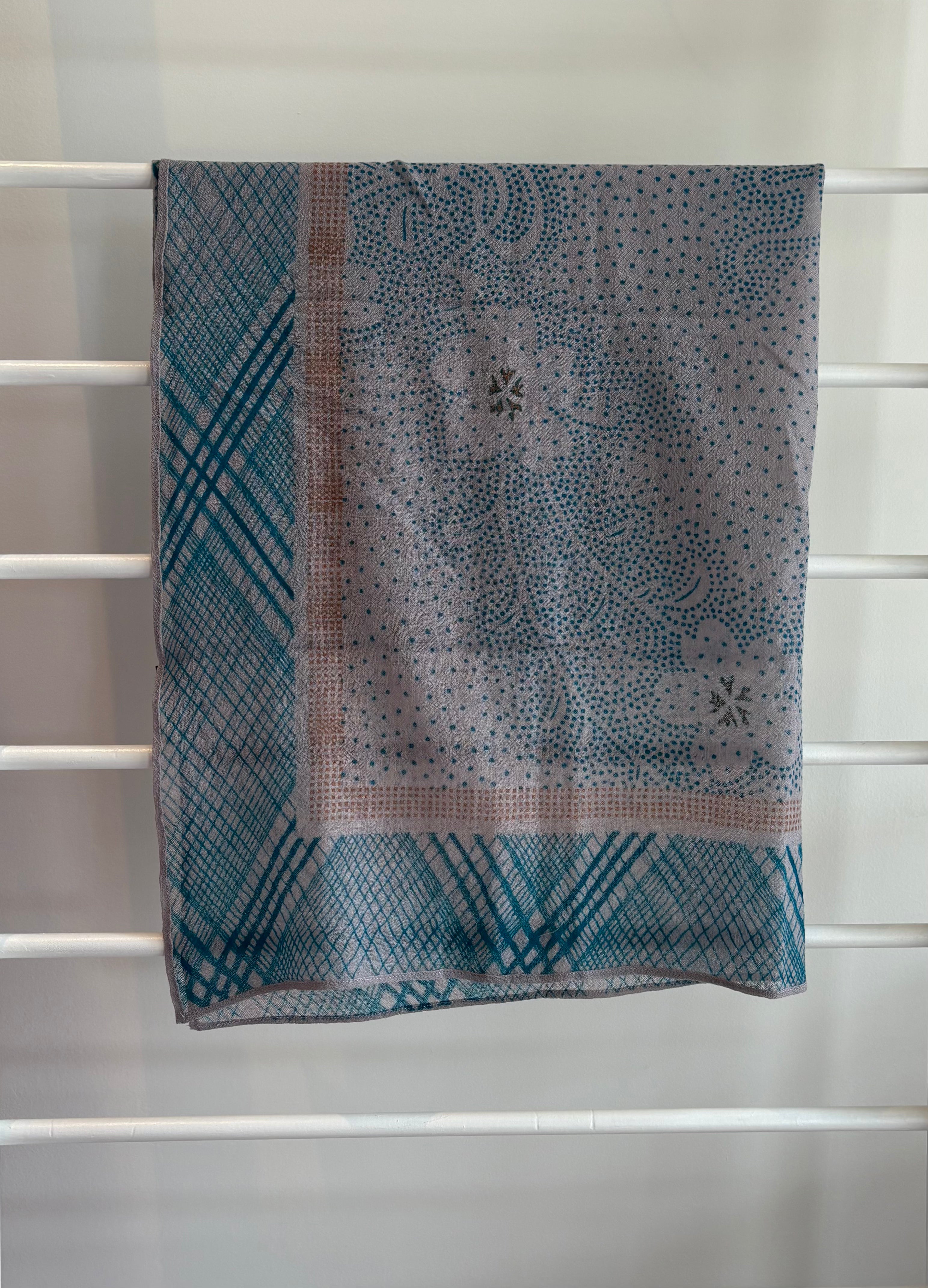 hanging lightweight wool scarf on rack with orange, blue and pink design.