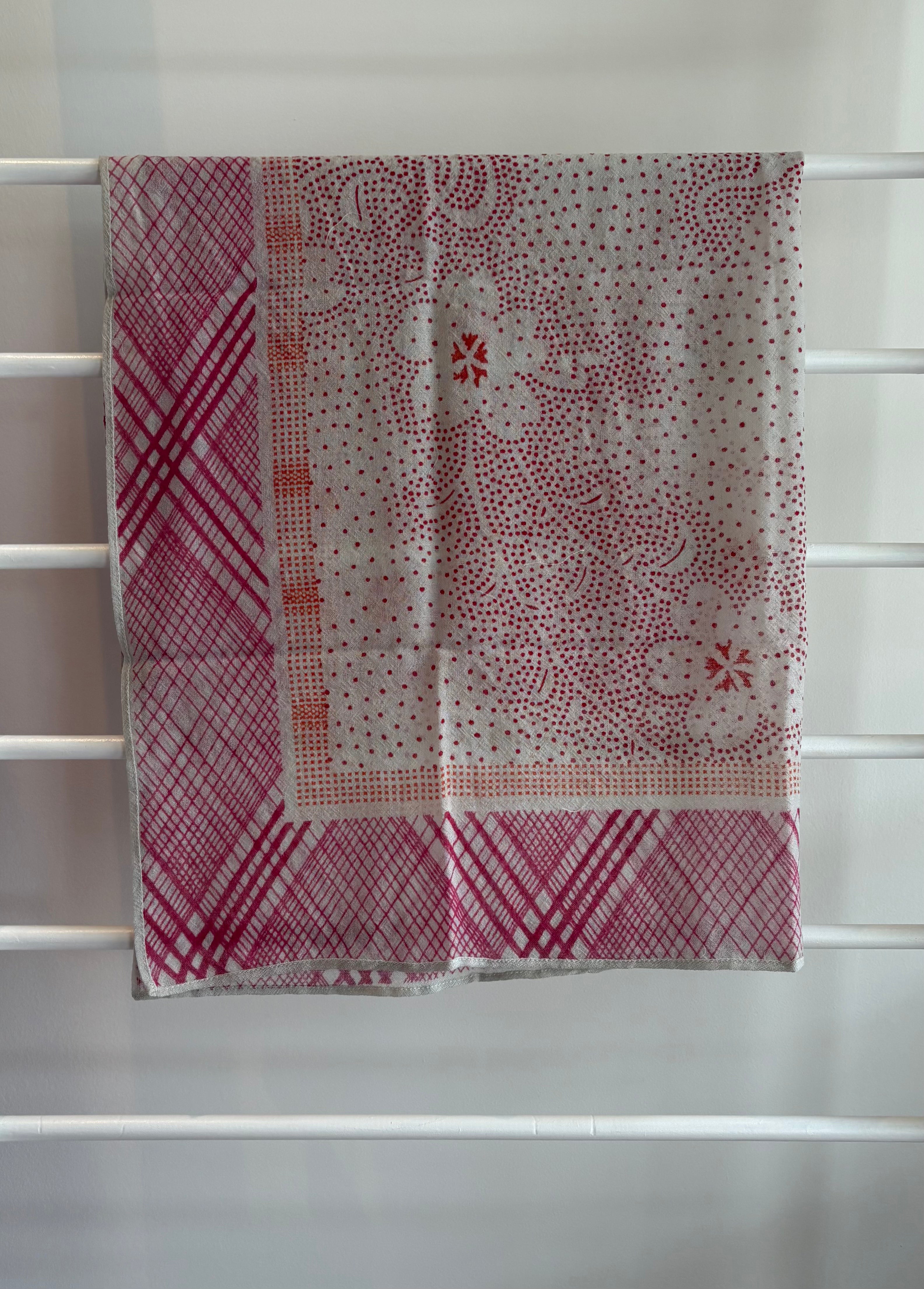 hanging lightweight wool scarf on rack with red, orange and white design.