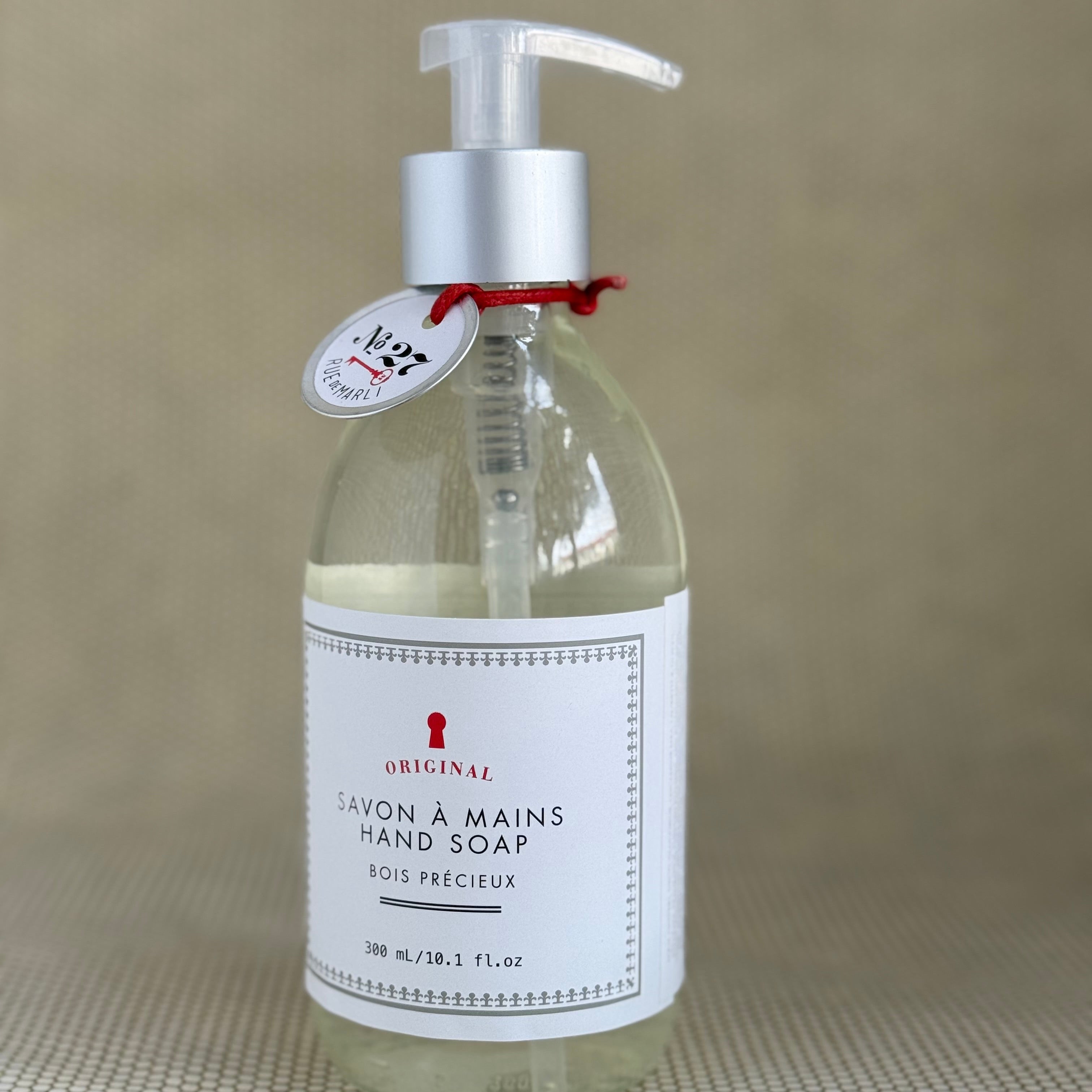 rue de marli glass liquid hand soap bottle with pump on neutral background. 