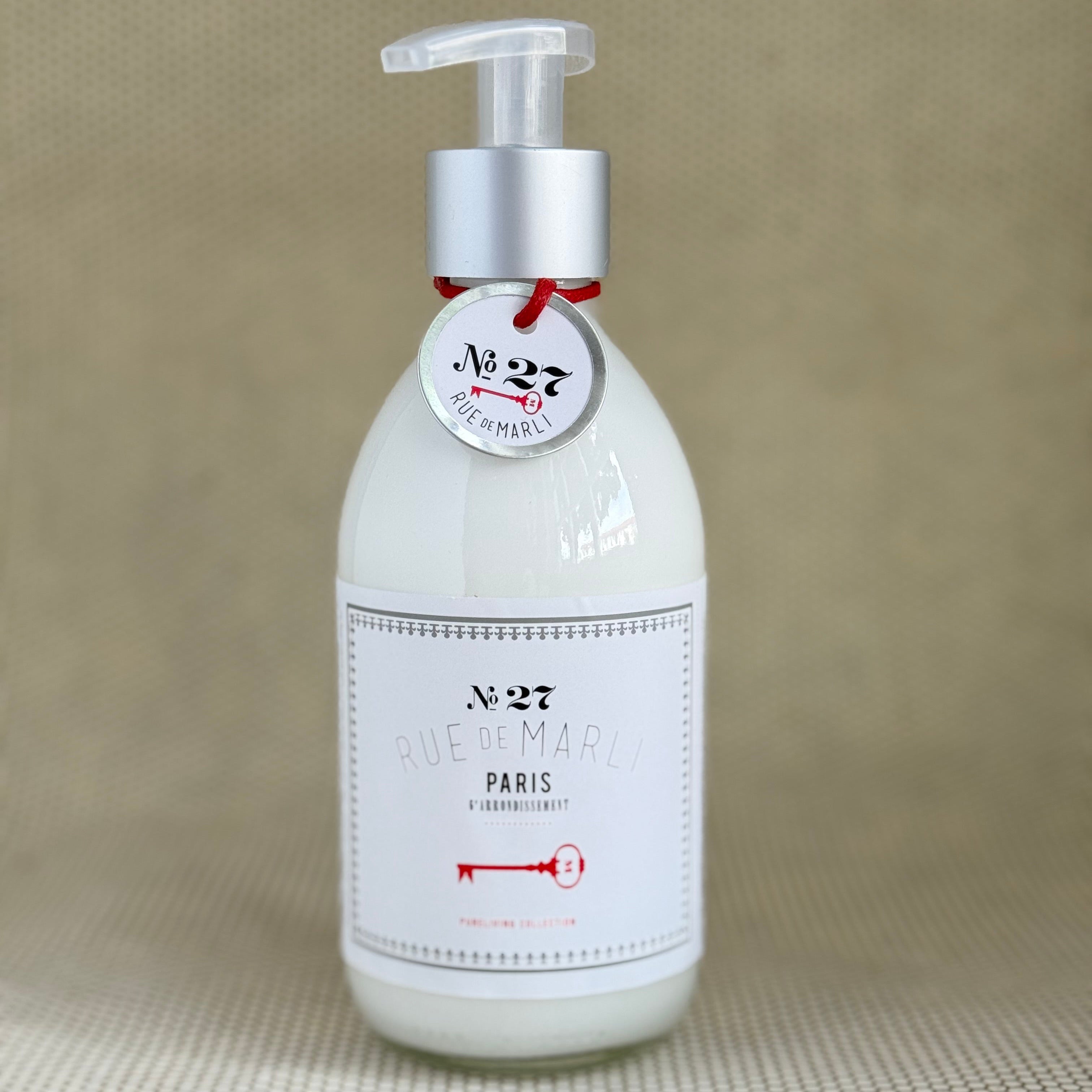 glass bottle of rue de marli body lotion with white label on neutral background. 