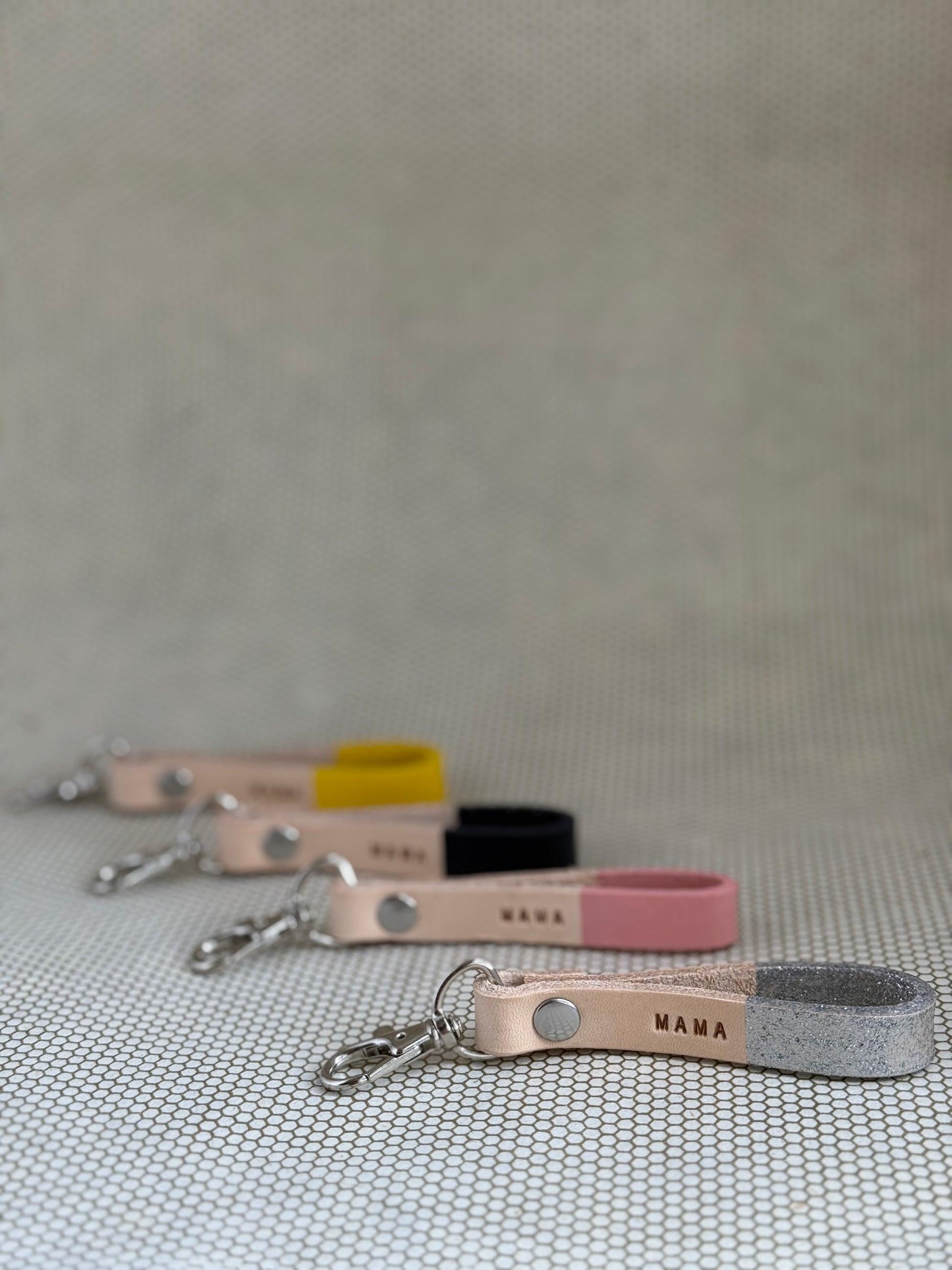 Set of varying color keychains with leather straps and "mama" lettering on leather. 