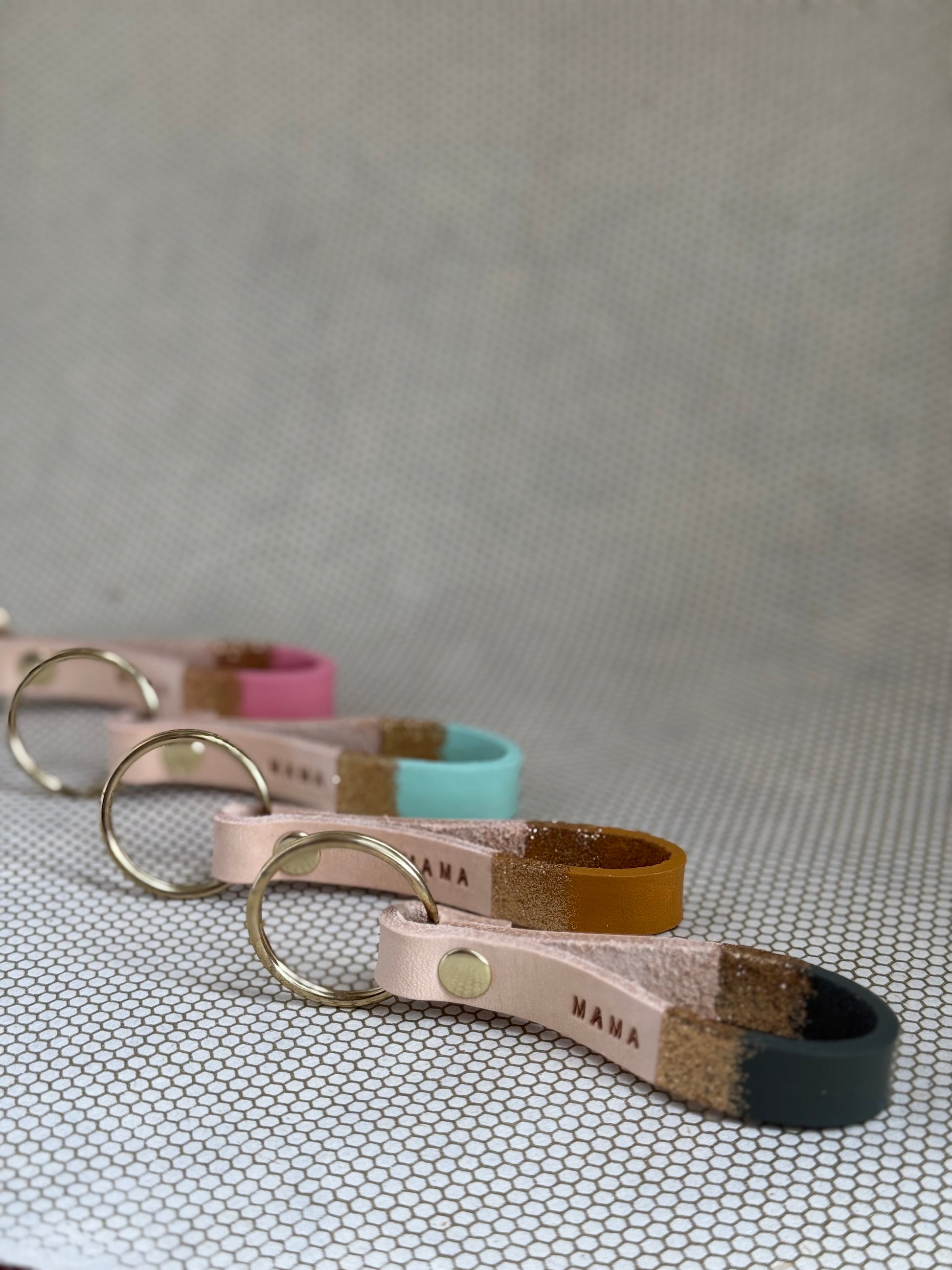 Set of varying color keychains with leather straps and "mama" lettering on leather. 