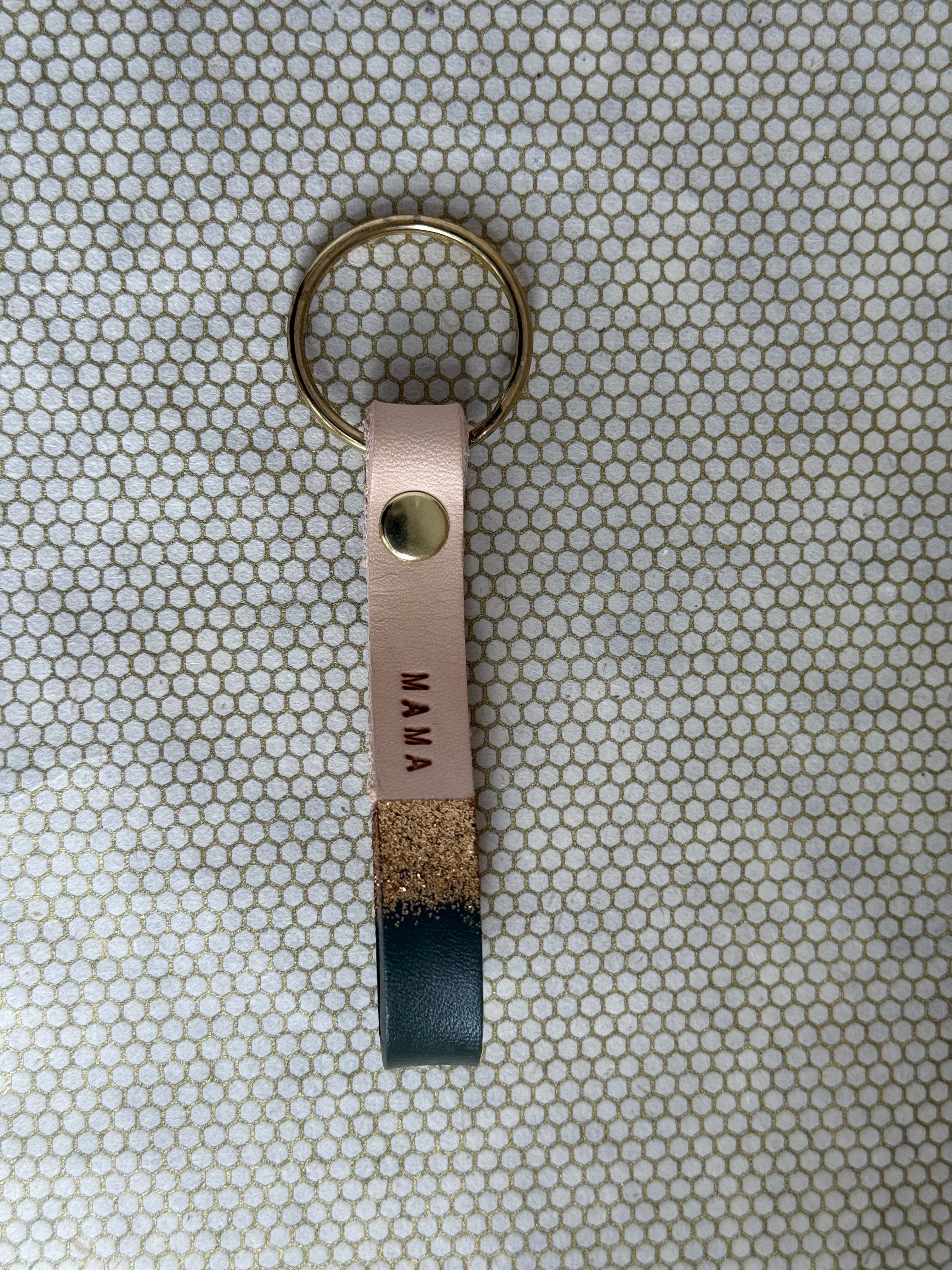 Keychain with black leather tag labeled 'MAMA' on a textured surface