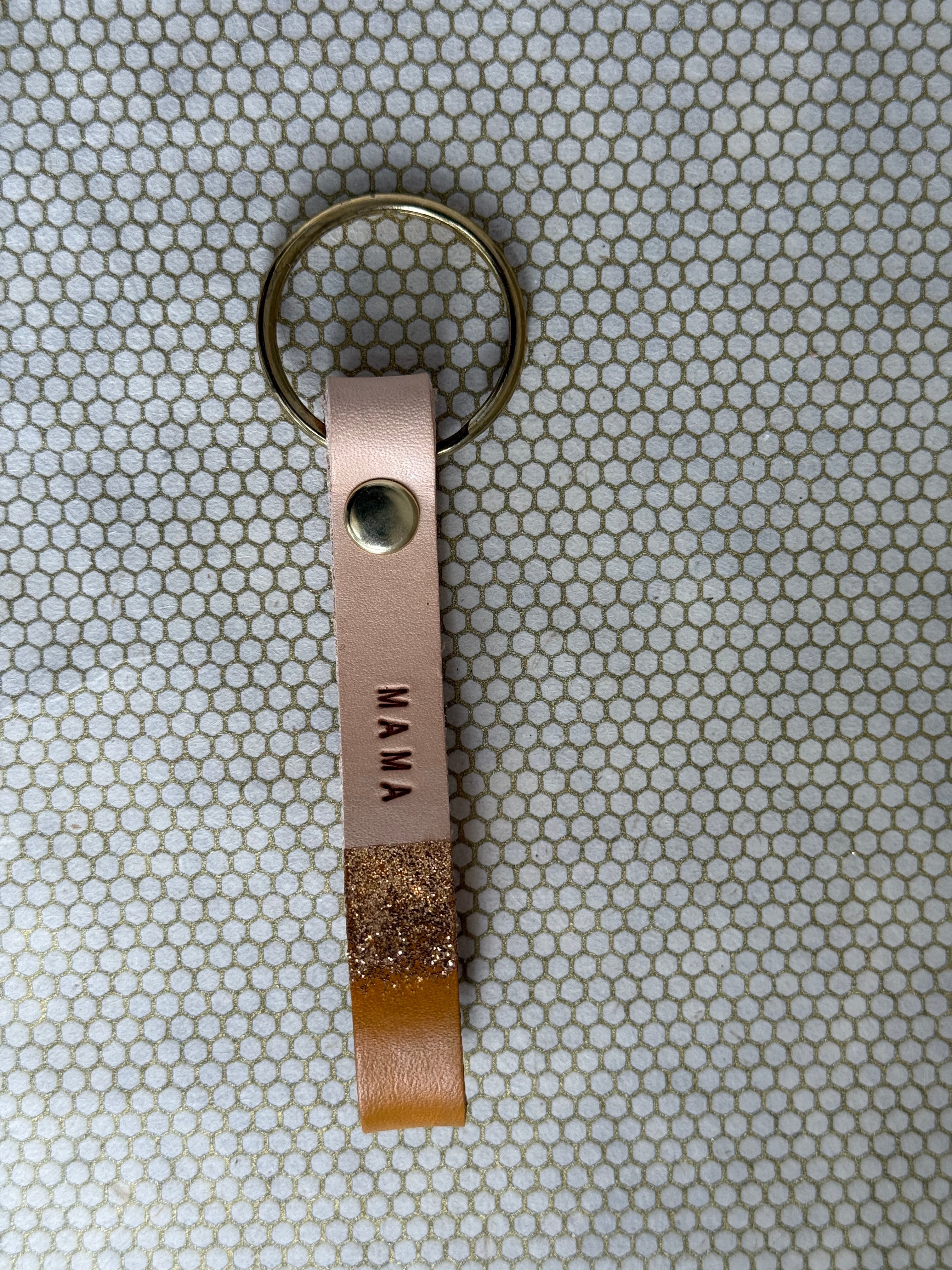 Leather rust colored keychain with 'MAMA' engraving on a textured surface