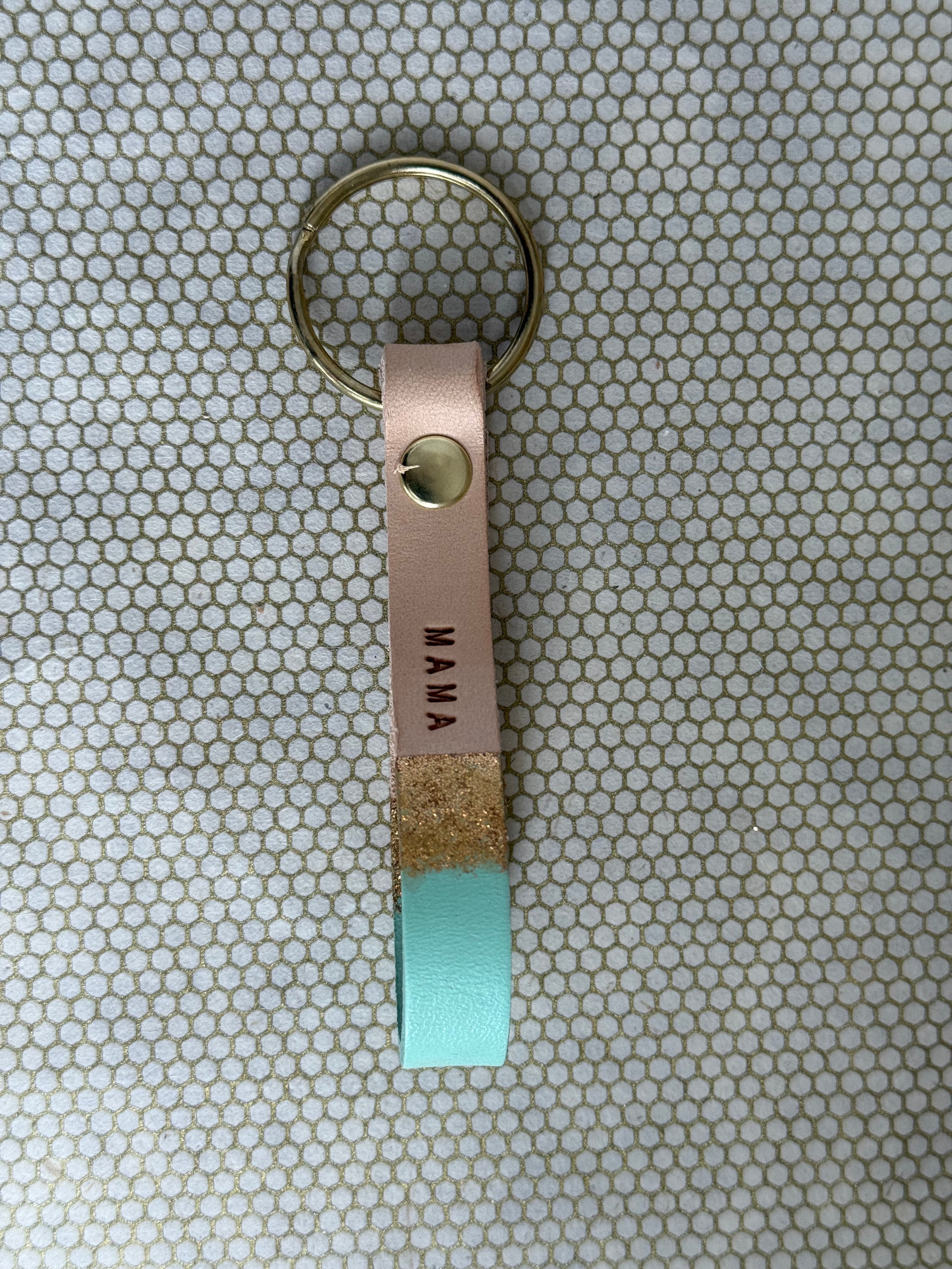 MAMA Keychain with leather tag and turquoise accent on a patterned background