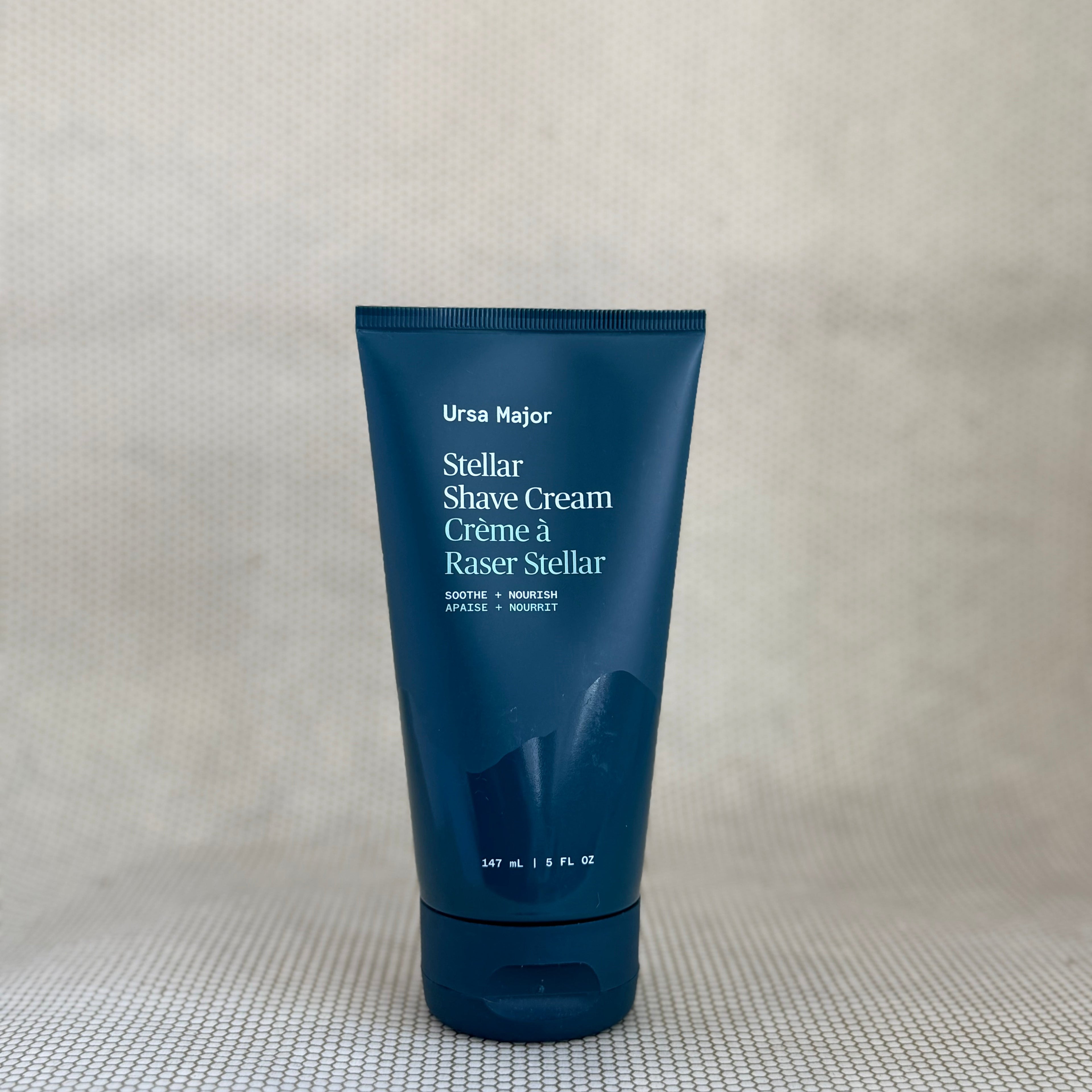 Tube if Ursa Major stellar shave cream in dark blue packaging on neutral background. 