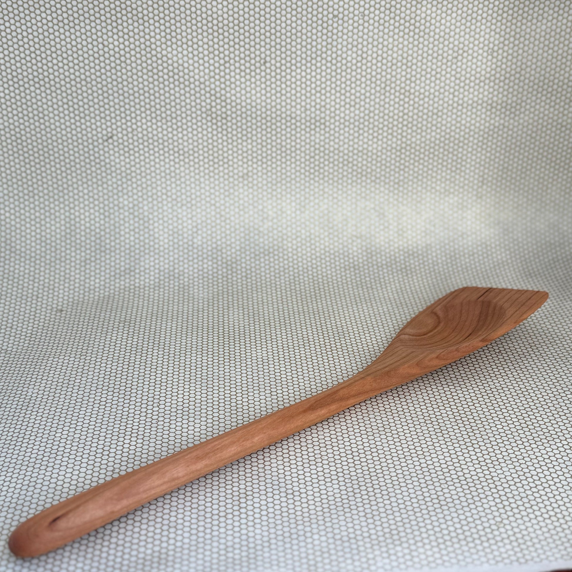 Wooden spoon on a textured white surface, Jonathan spoon