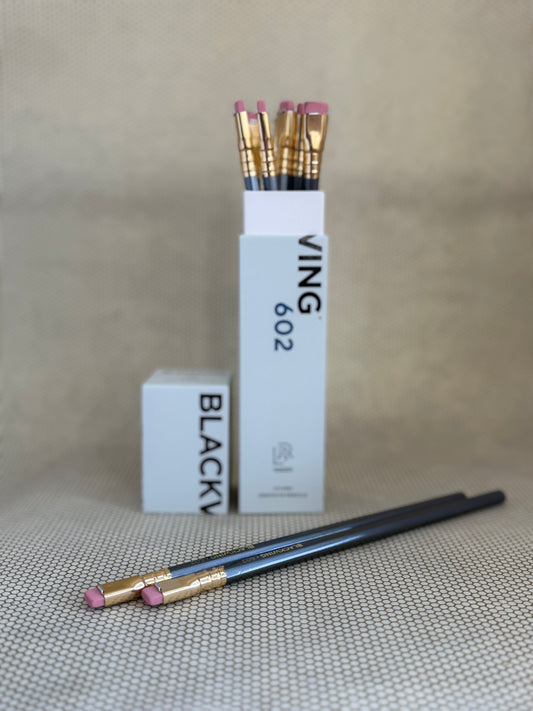 white box of Blackwing 602 pencils with erasers and dark grey shells on neutral background. 