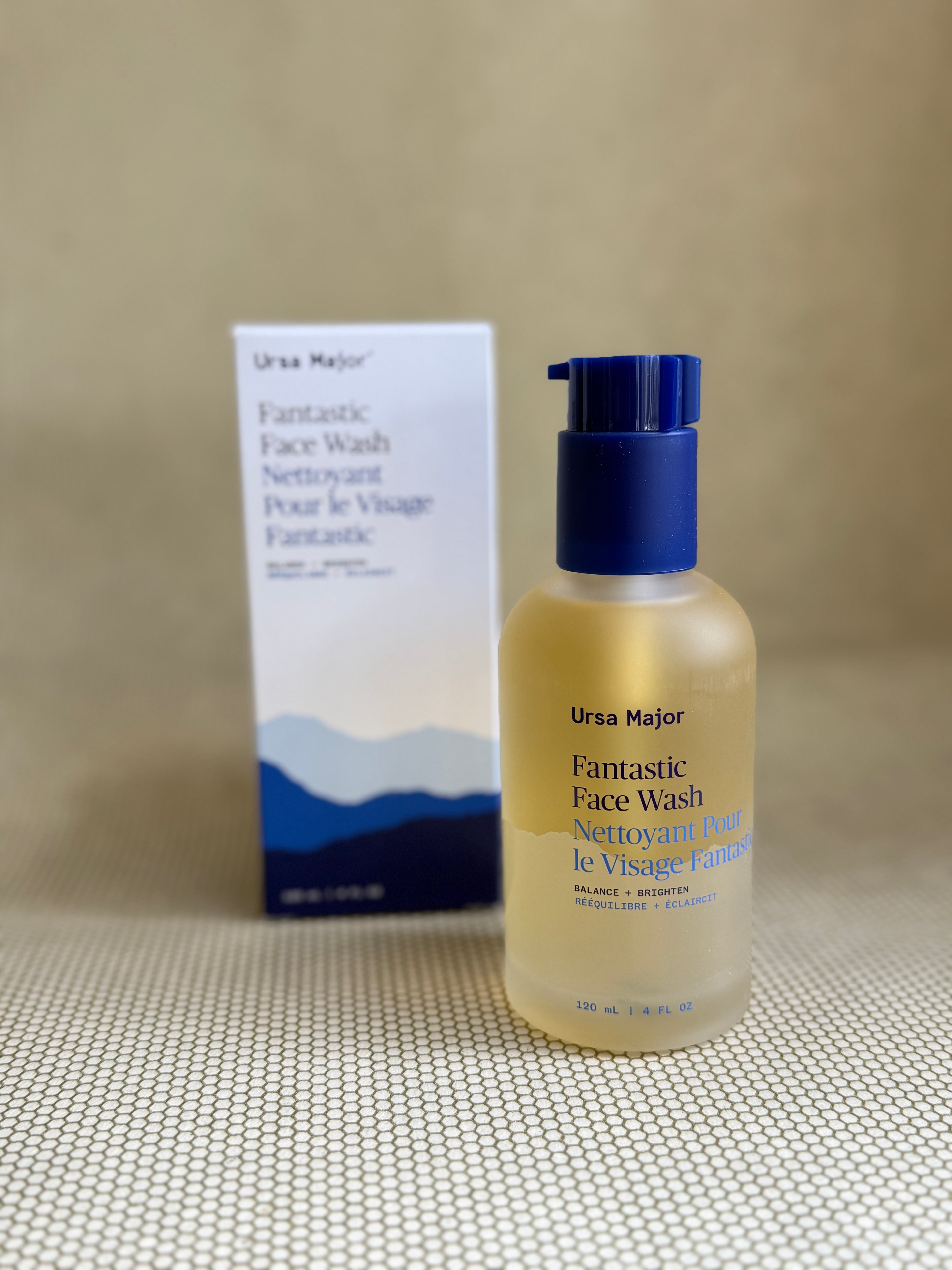 glass bottle of Ursa Major Fantastic Face Wash and white and blue box on a textured gray background