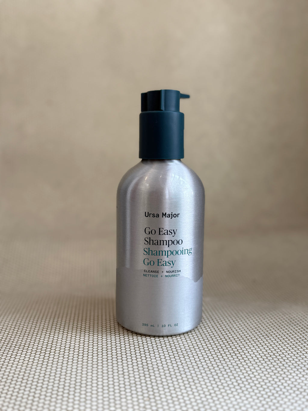 metallic bottle of Ursa Major "go easy" shampoo with pump on neutral background.