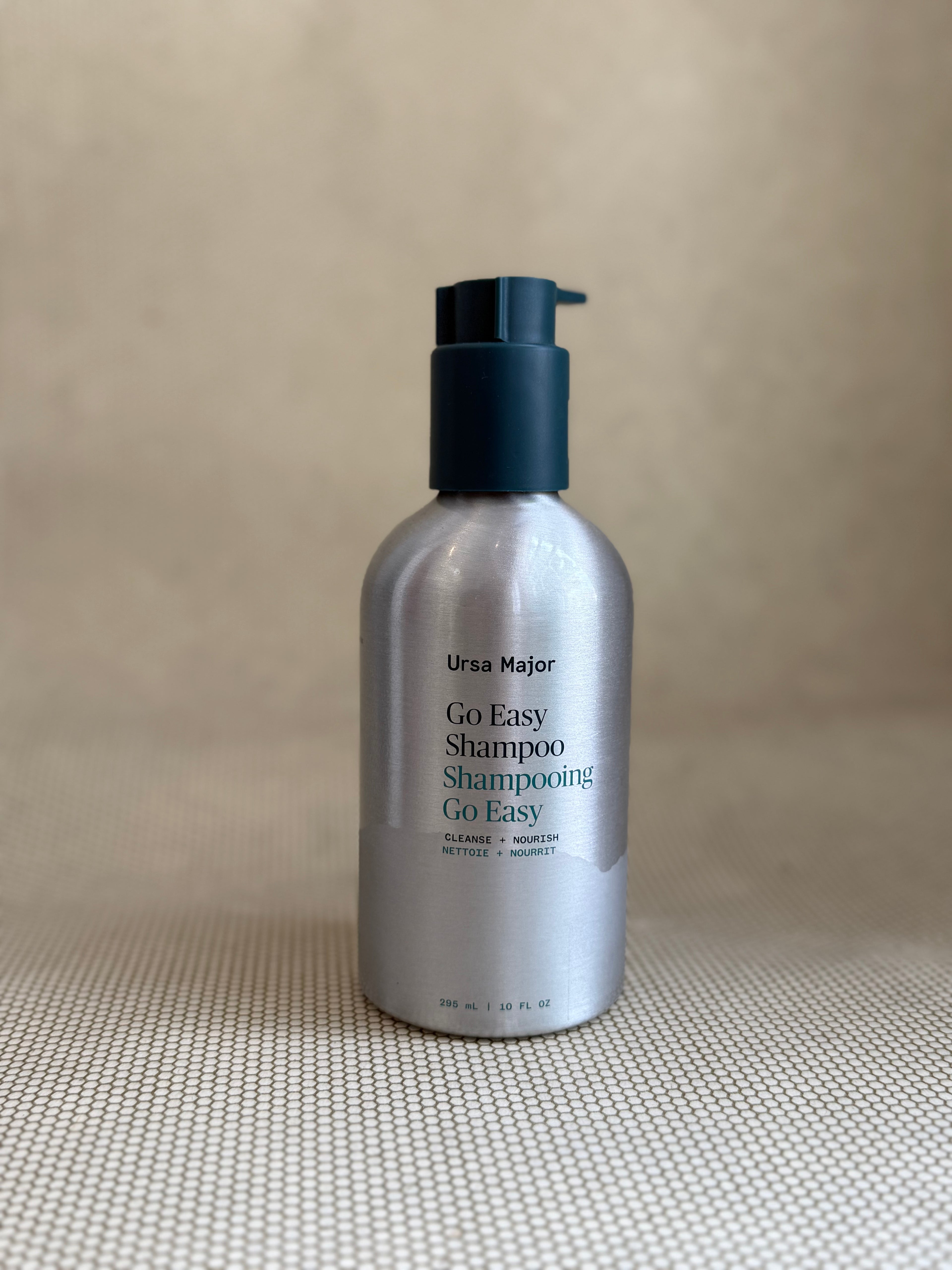 metallic bottle of Ursa Major "go easy" shampoo with pump on neutral background.