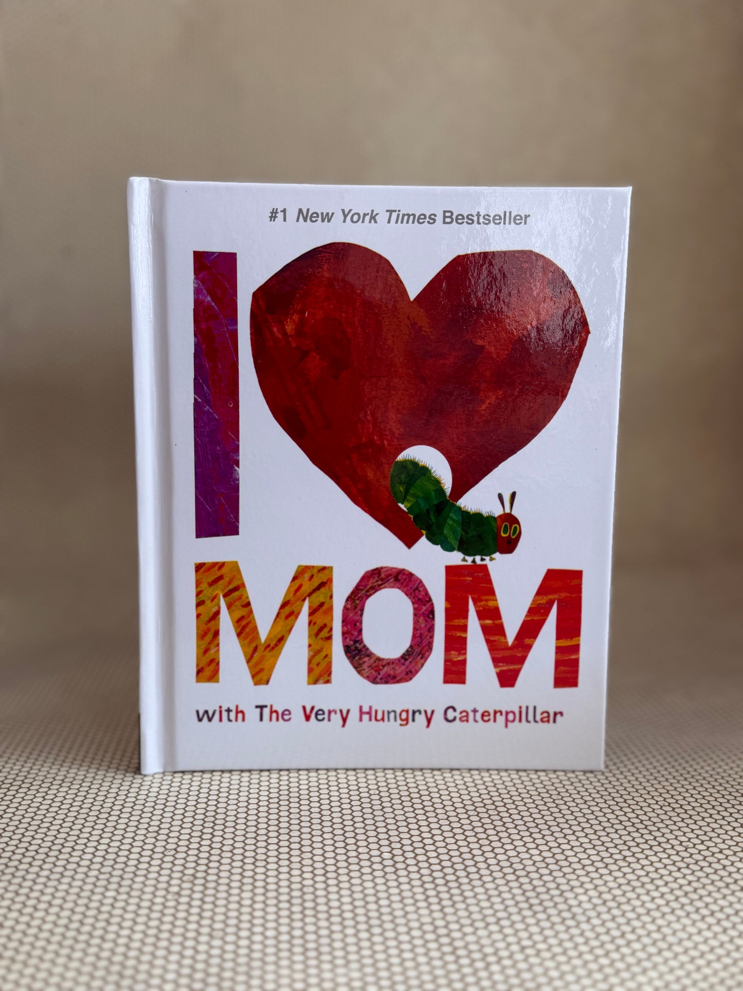 Book titled 'I ❤️ Mom with The Very Hungry Caterpillar' on a textured surface.
