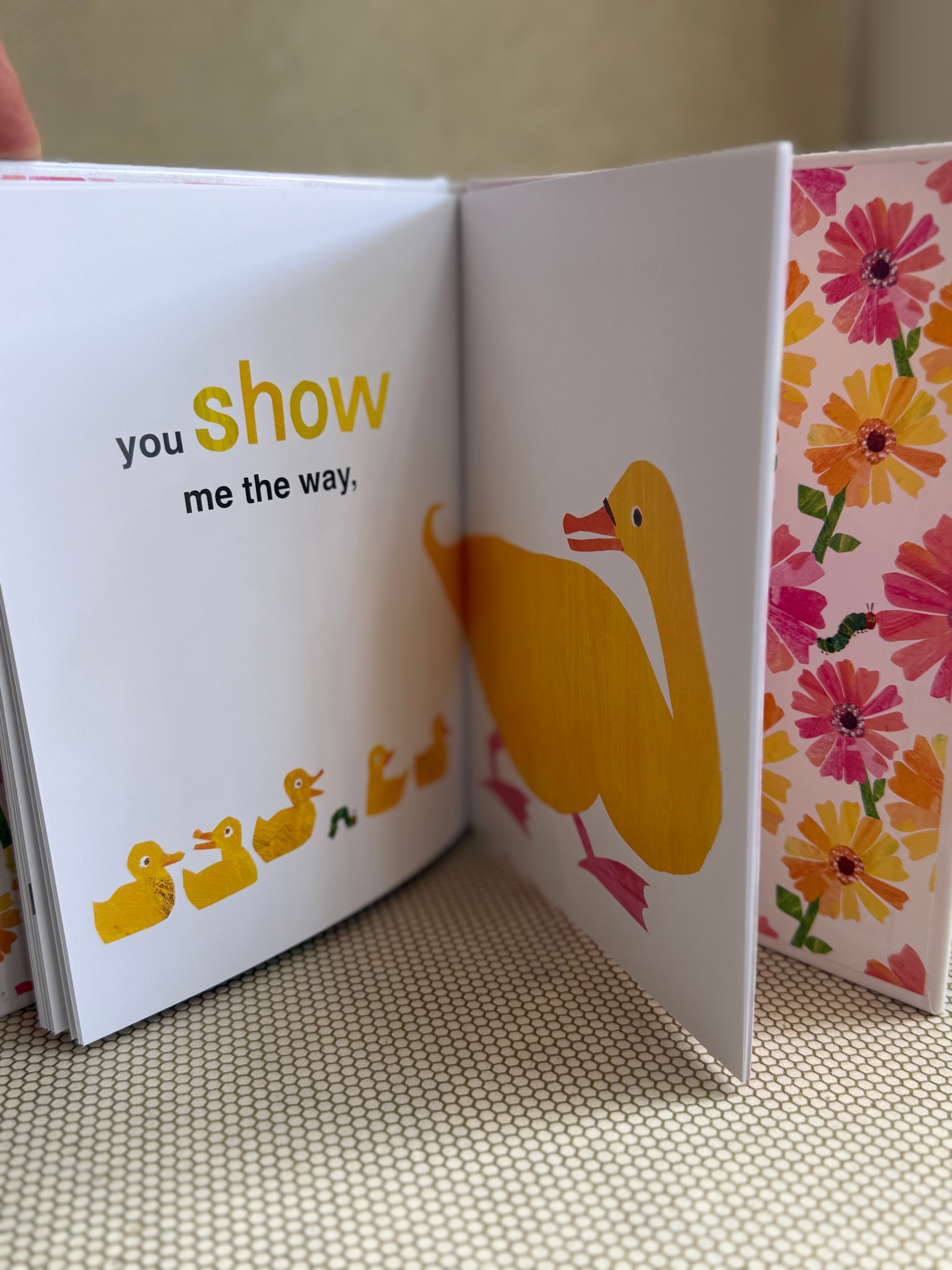 Open book with a yellow duck and text on a floral background
