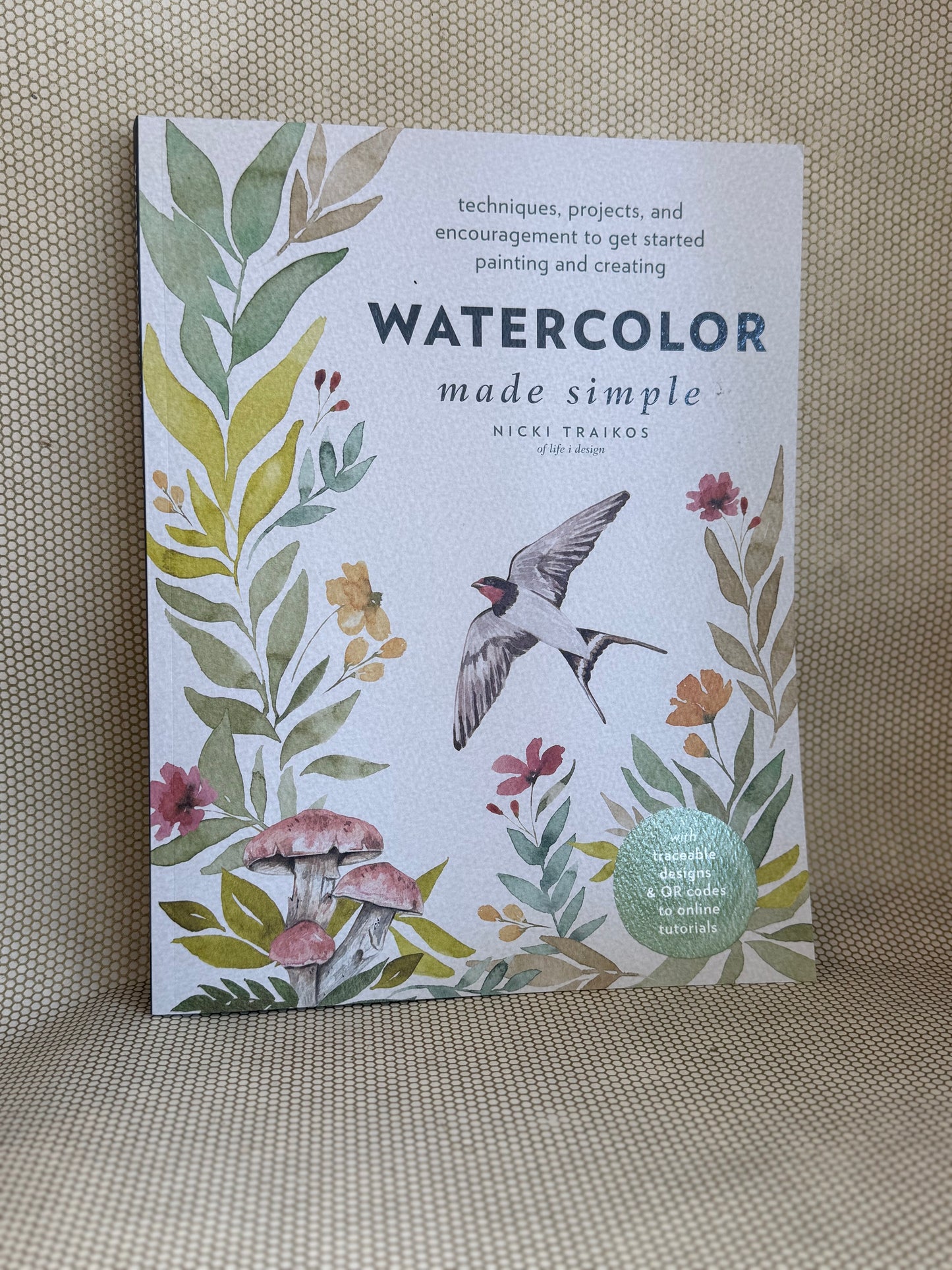 Book titled 'Watercolor Made Simple' with floral and bird design on a textured surface