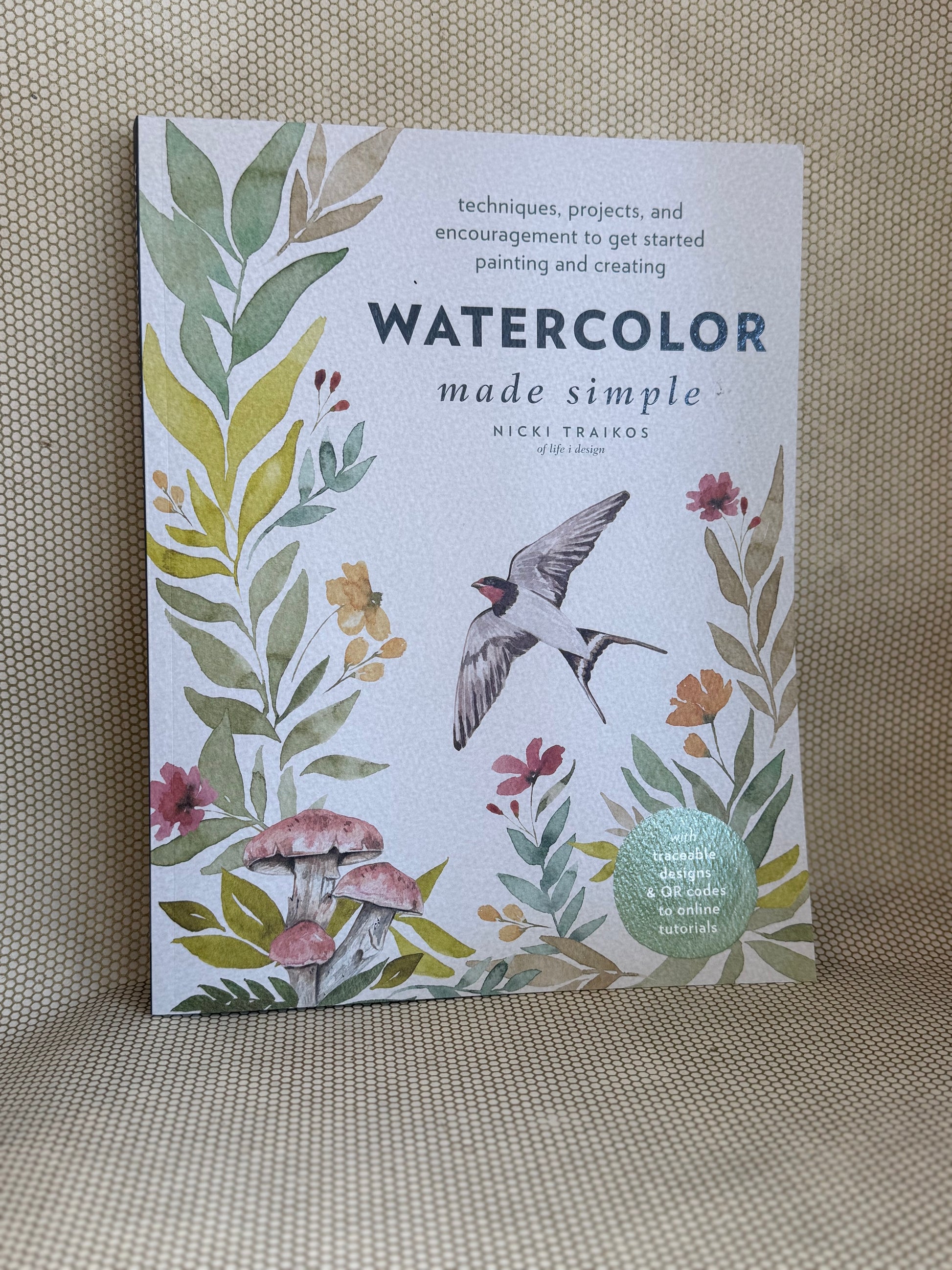 Book titled 'Watercolor Made Simple' with floral and bird design on a textured surface