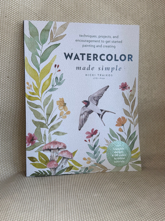 Book titled 'Watercolor Made Simple' with floral and bird design on a textured surface