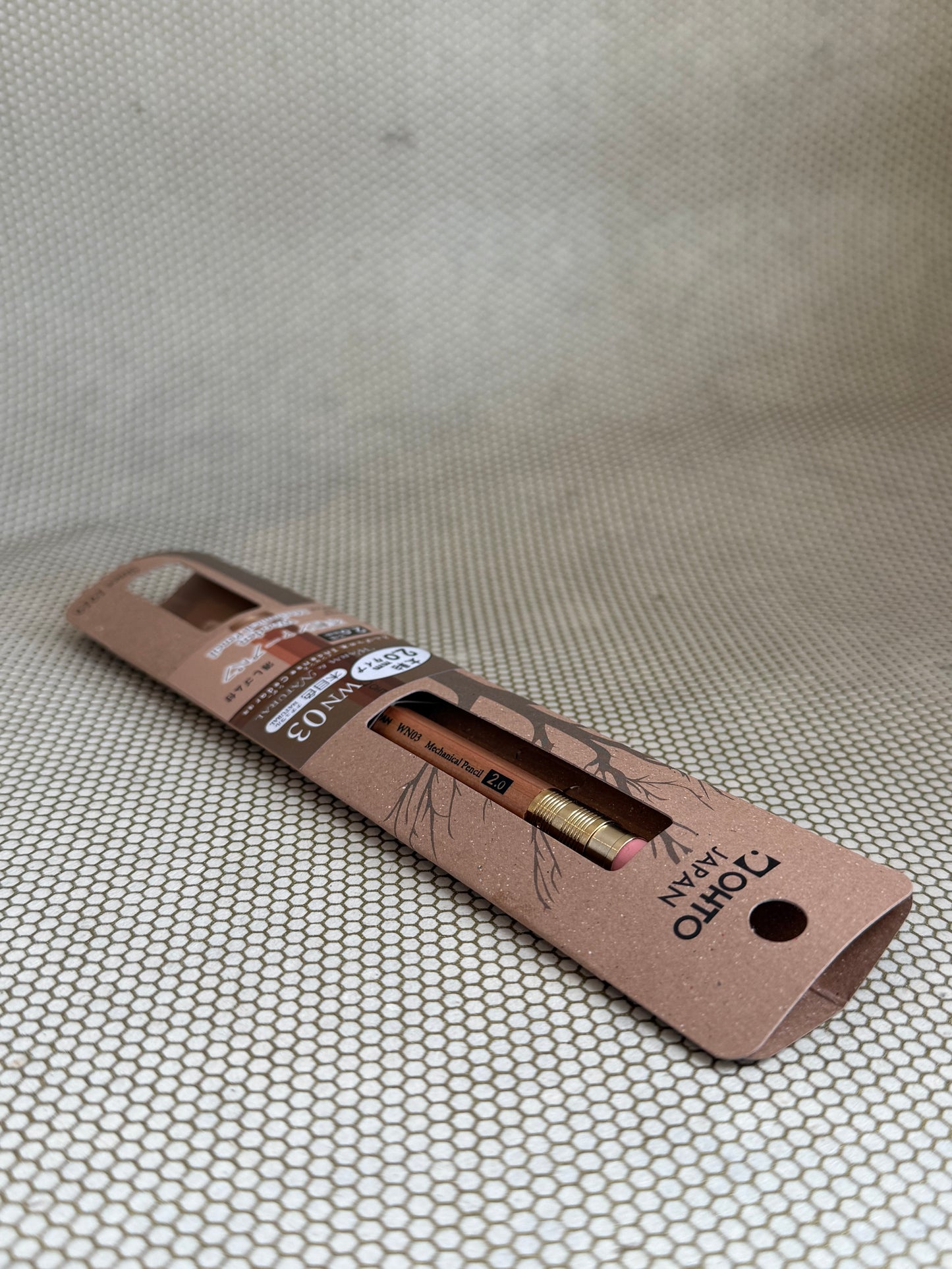 large wooden mechanical pencil with eraser on neutral background in cardboard packaging. 