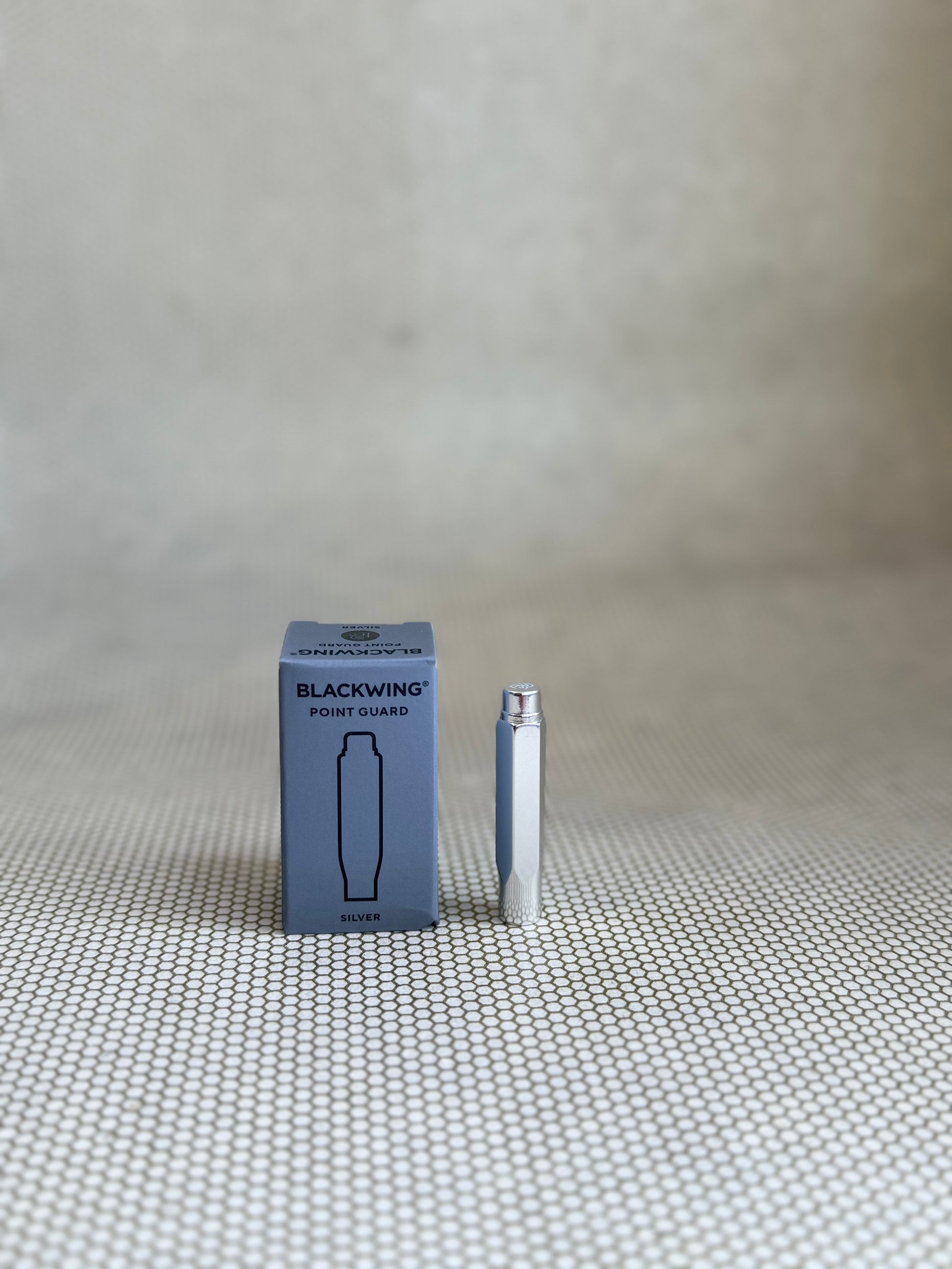 Blackwing product packaging and pen on a textured surface with a neutral background