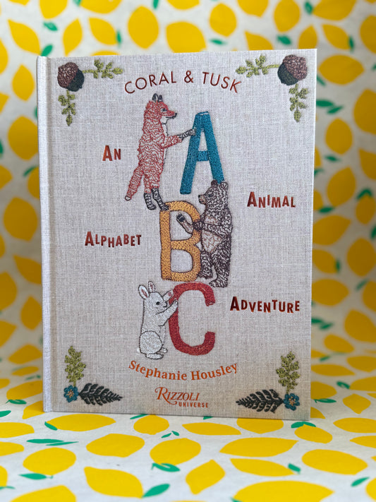 Book titled 'Coral & Tusk: An Alphabet ABC Animal Adventure' by Stephanie Housley on a yellow floral background