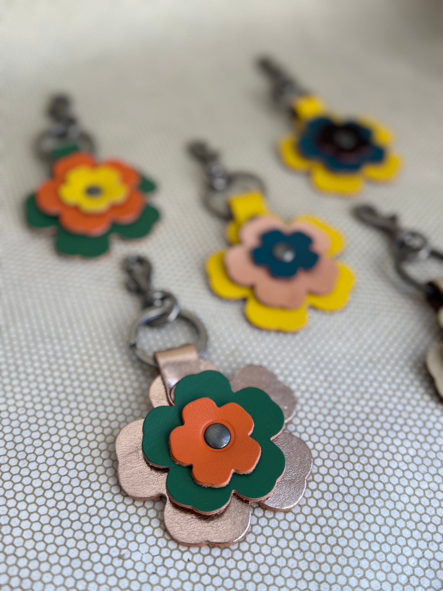 Floral leather keychain charms on a textured surface