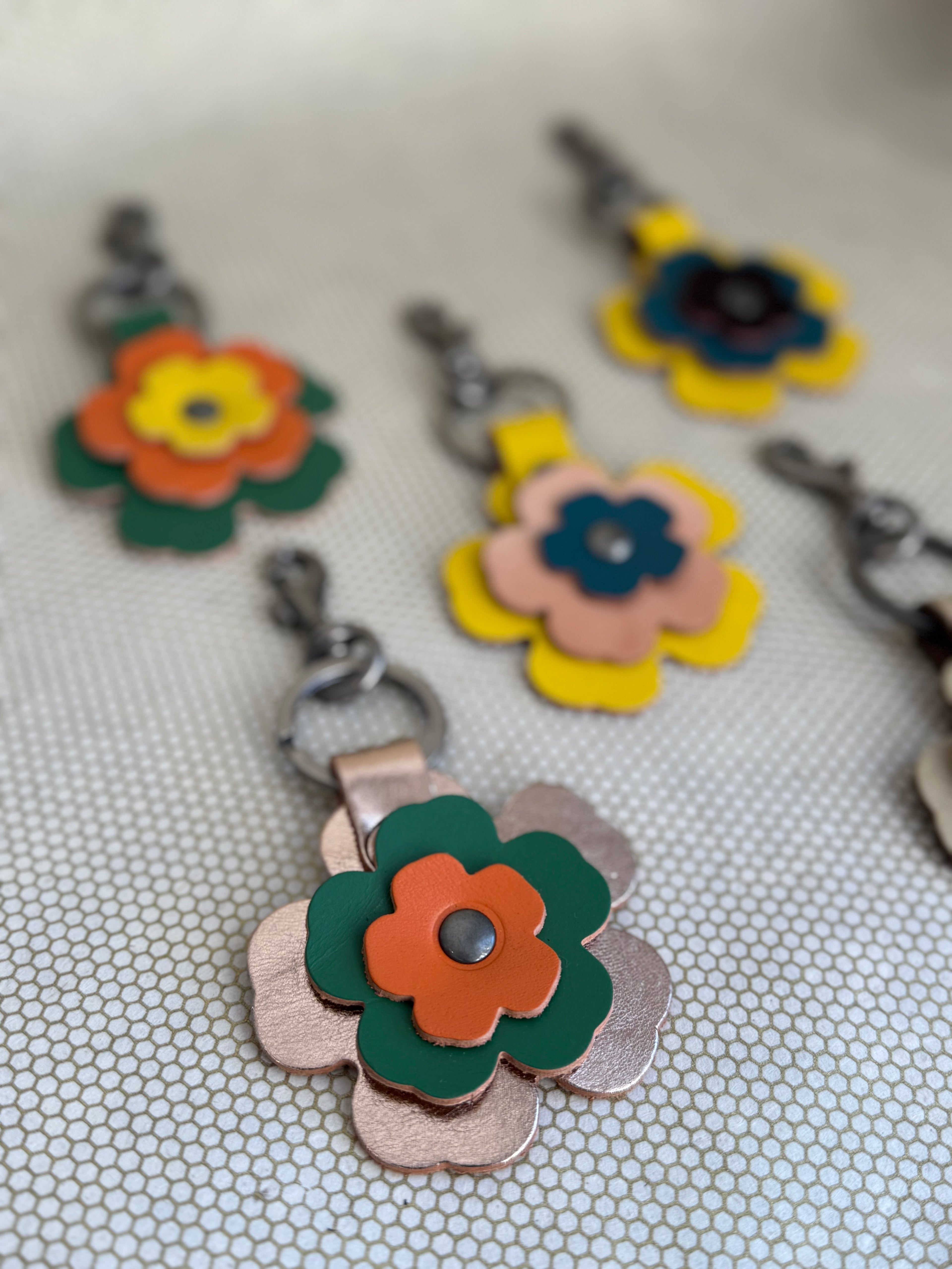 Floral leather keychain charms on a textured surface