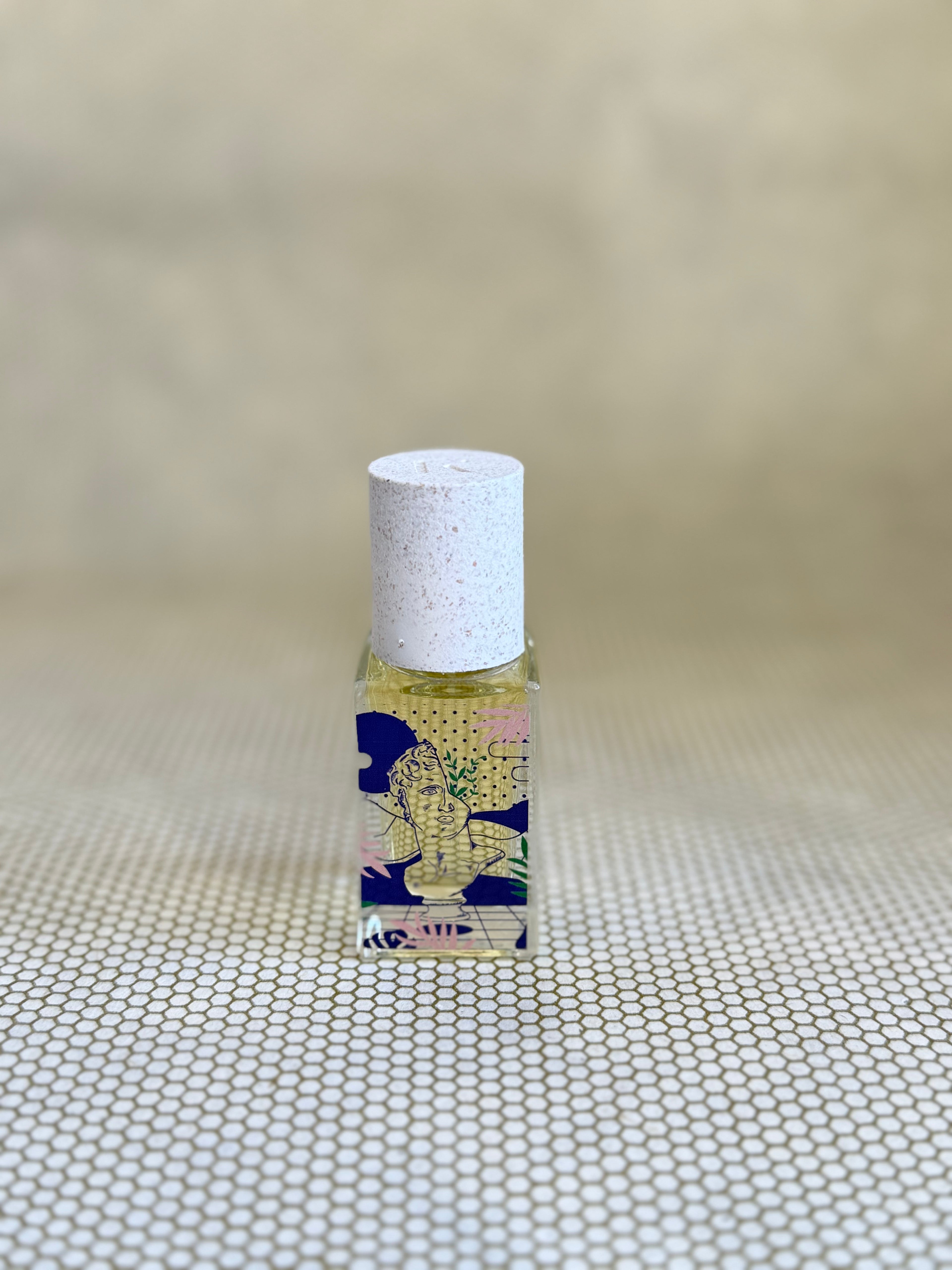 small glass bottle of maison matine perfume with greek bust graphic design on bottle. 