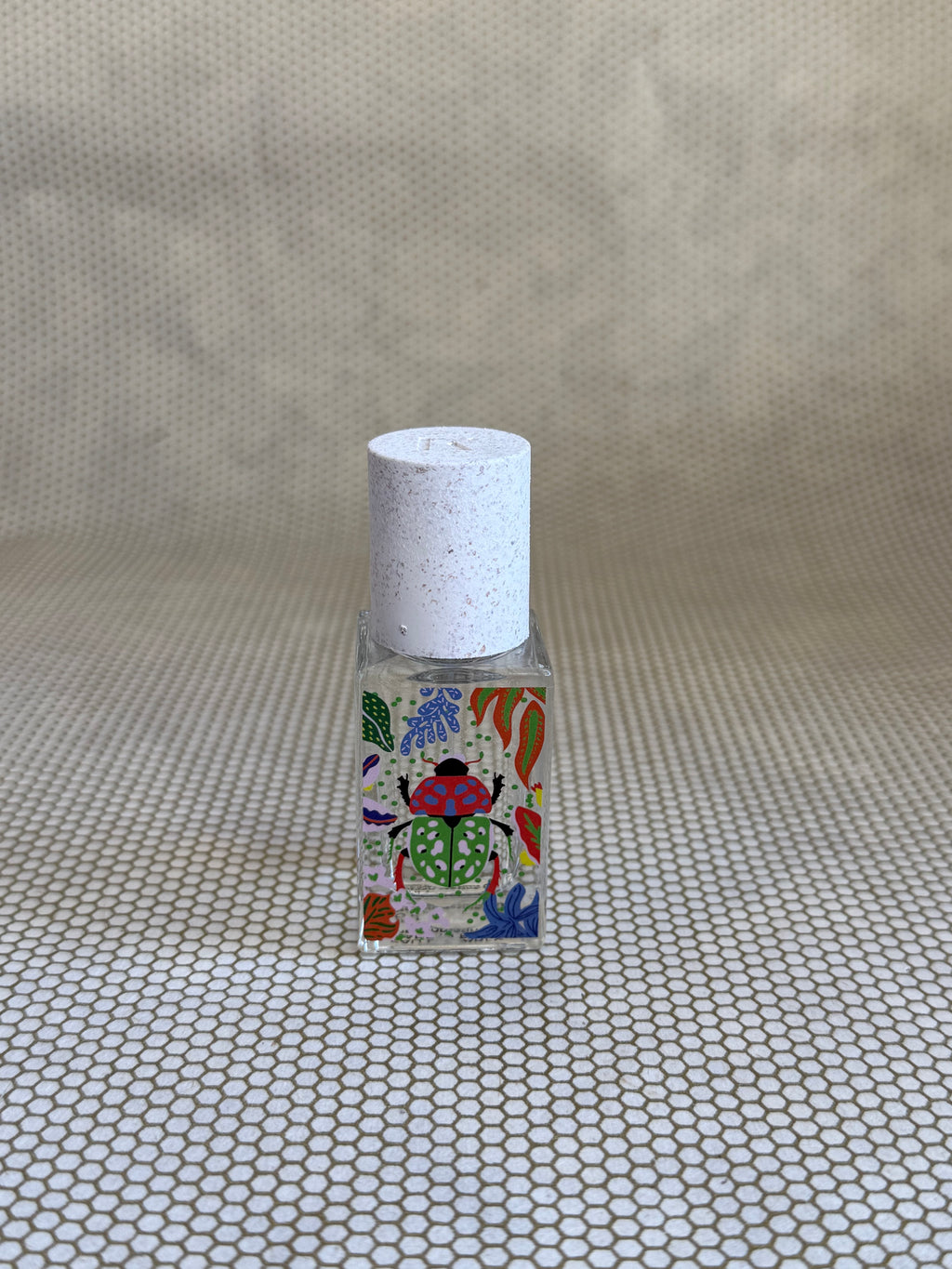 small bottle of maison matine perfume with beetle drawing design on bottle. 