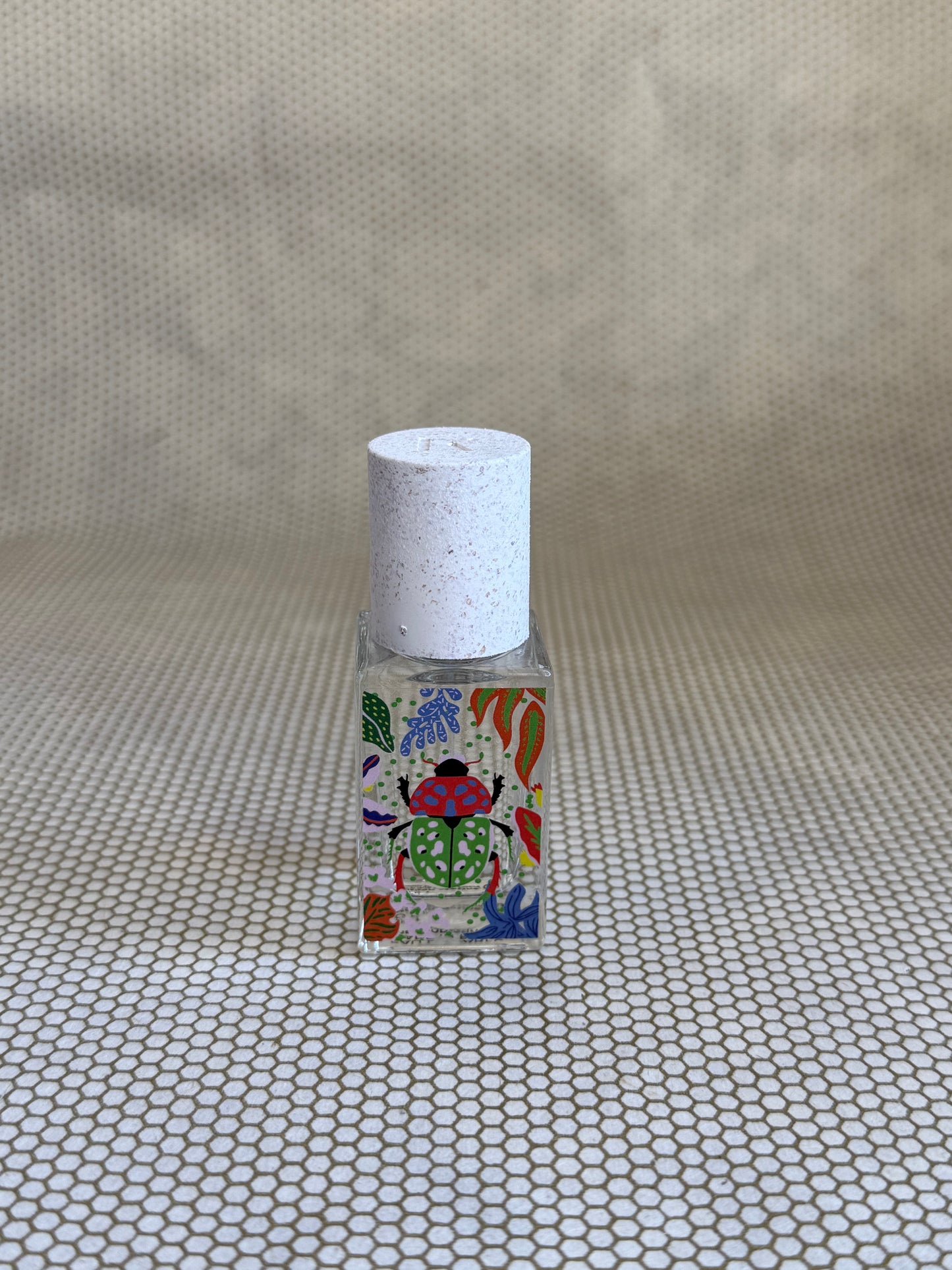 small bottle of maison matine perfume with beetle drawing design on bottle. 