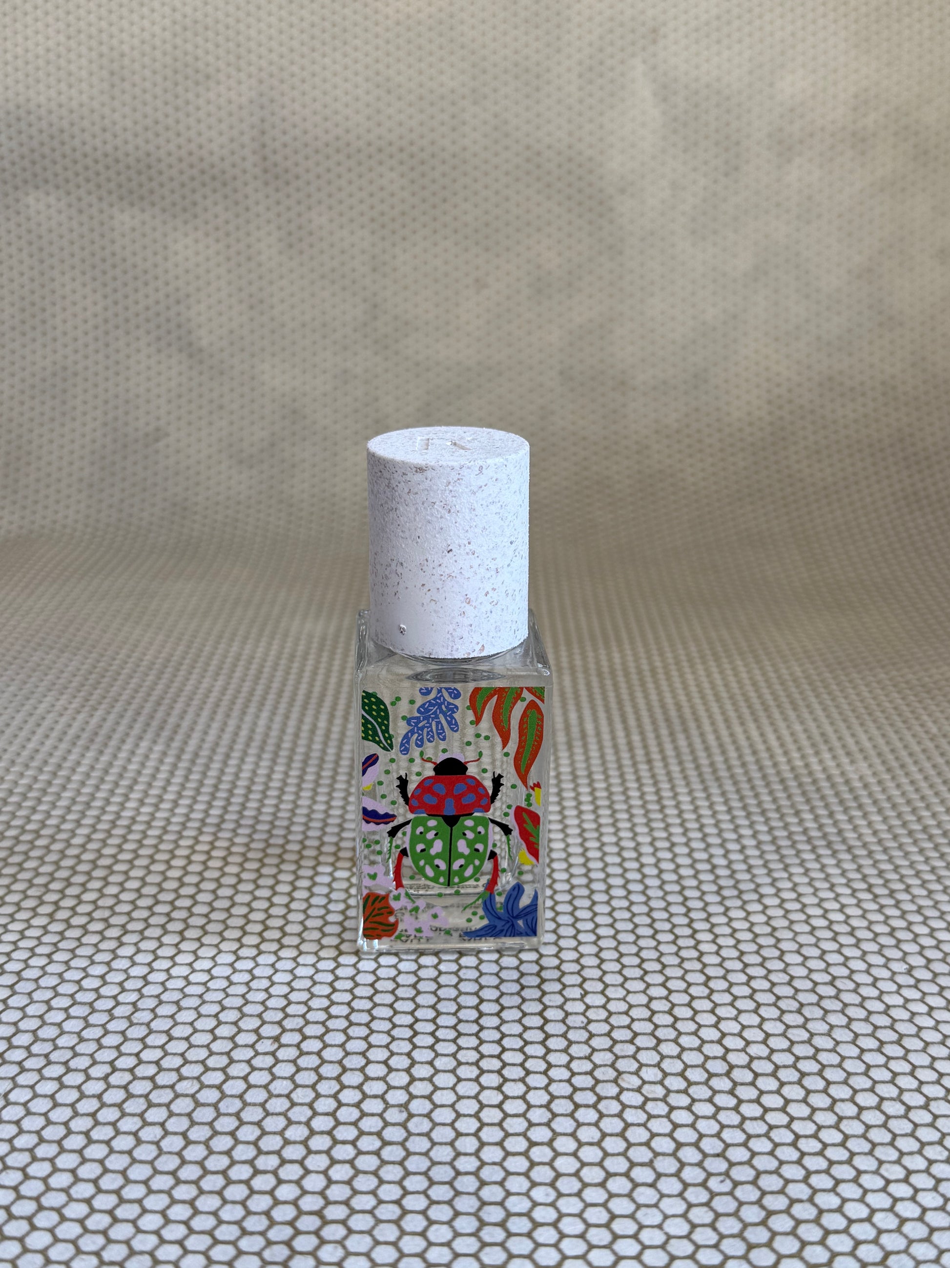 small bottle of maison matine perfume with beetle drawing design on bottle. 