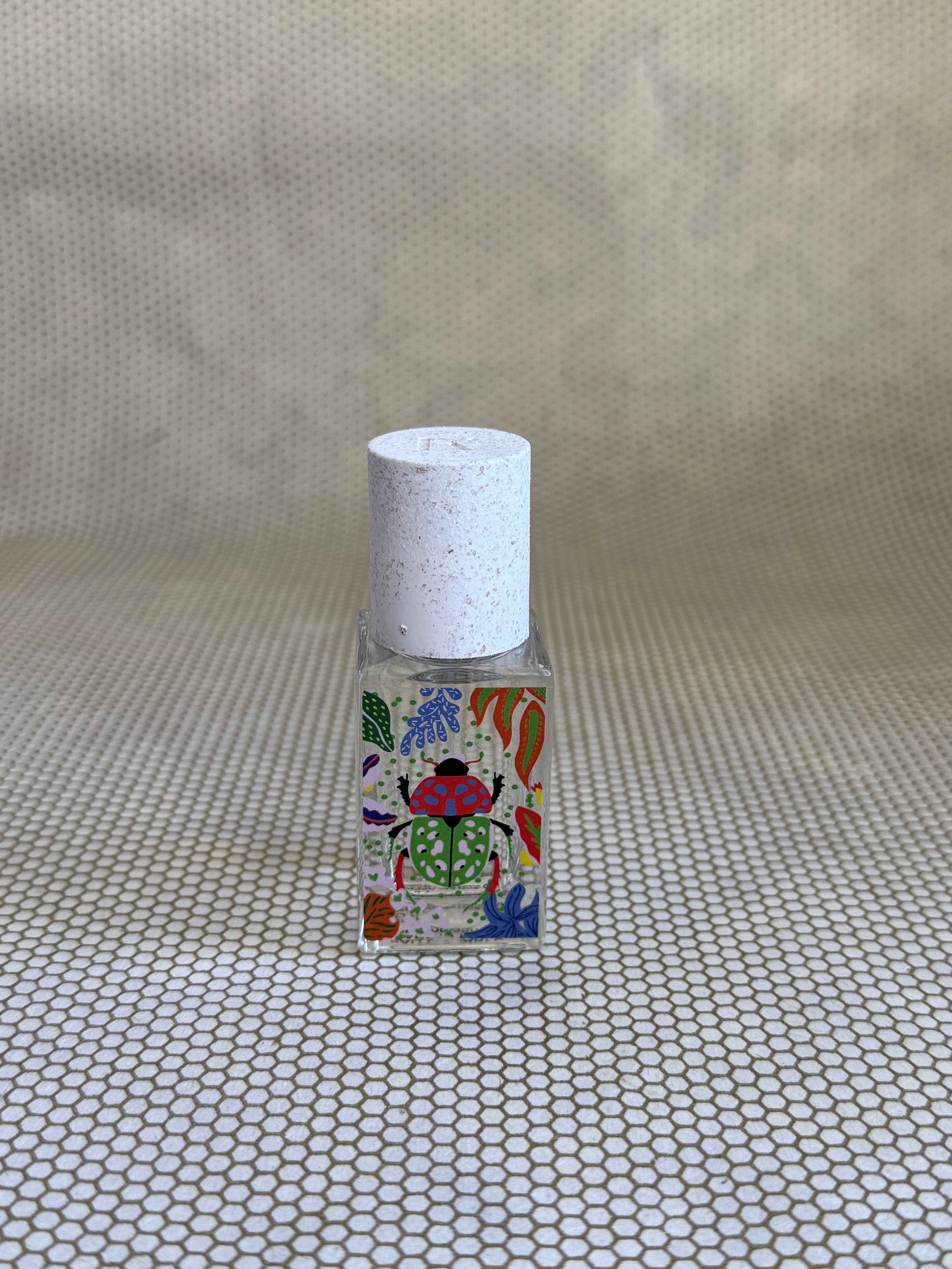 small bottle of maison matine perfume with beetle drawing design on bottle. 