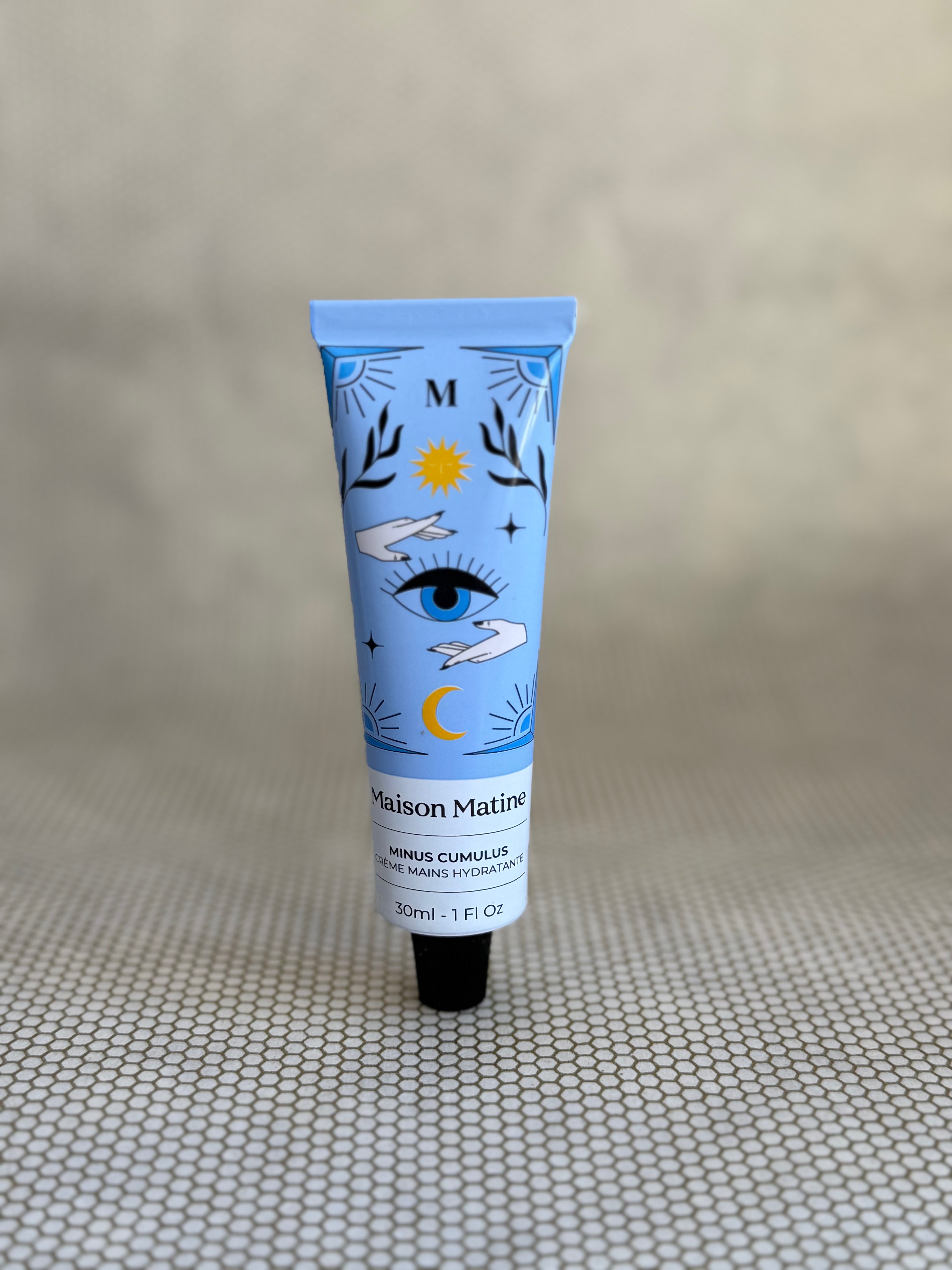 blue tube with artistic design of Maison Matine Minus Cumulus hand cream on neutral background. 