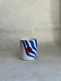 Maison Matine Rebel Candle. white and blue print with red accent on ceramic container. 