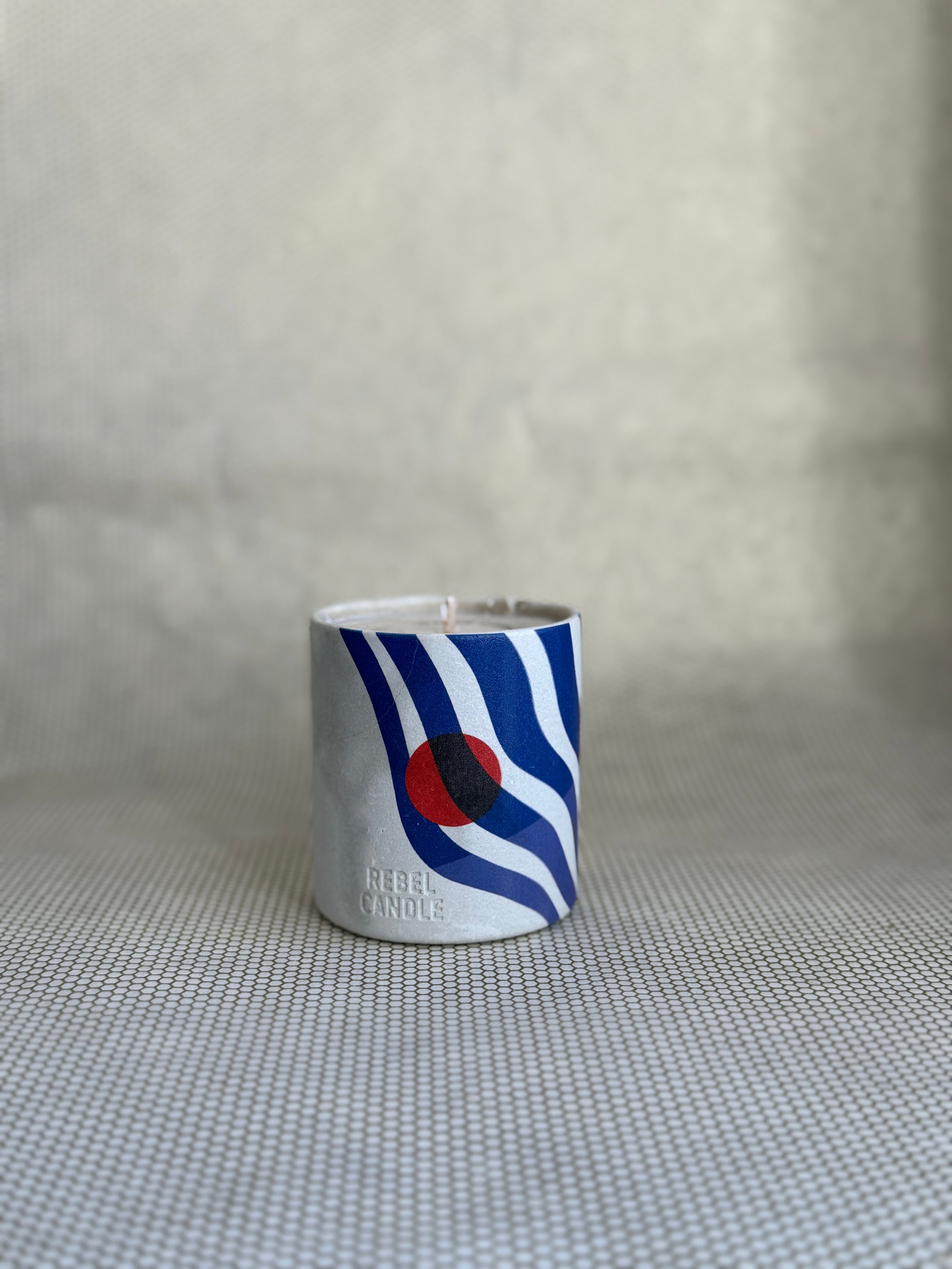 Maison Matine Rebel Candle. white and blue print with red accent on ceramic container. 