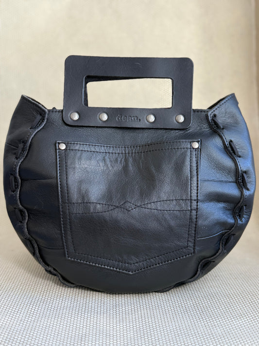 Black leather handbag with a unique handle design on a neutral background