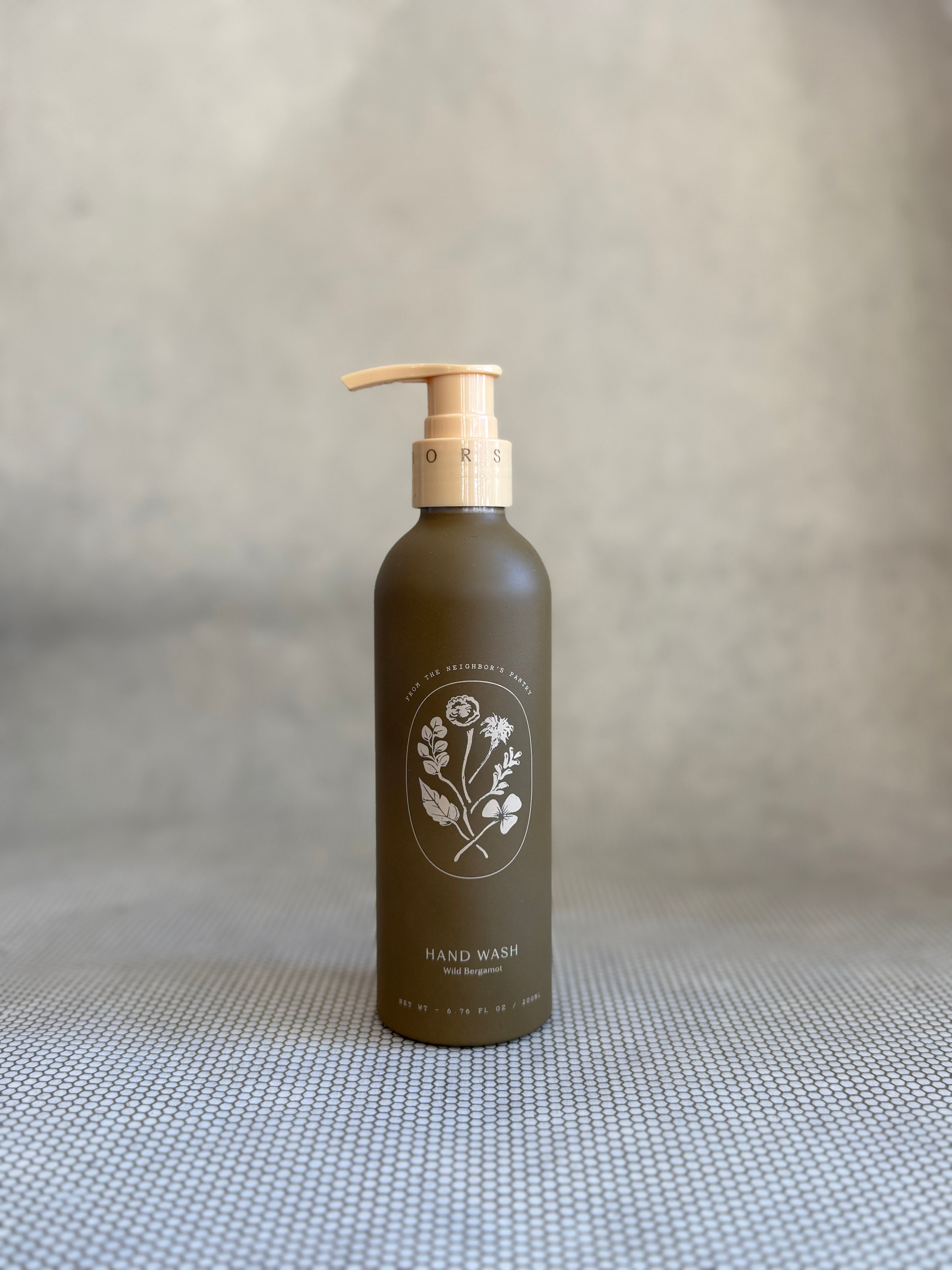 brown pump bottle of My Neighbor's wild bergamot hand wash with floral design. 