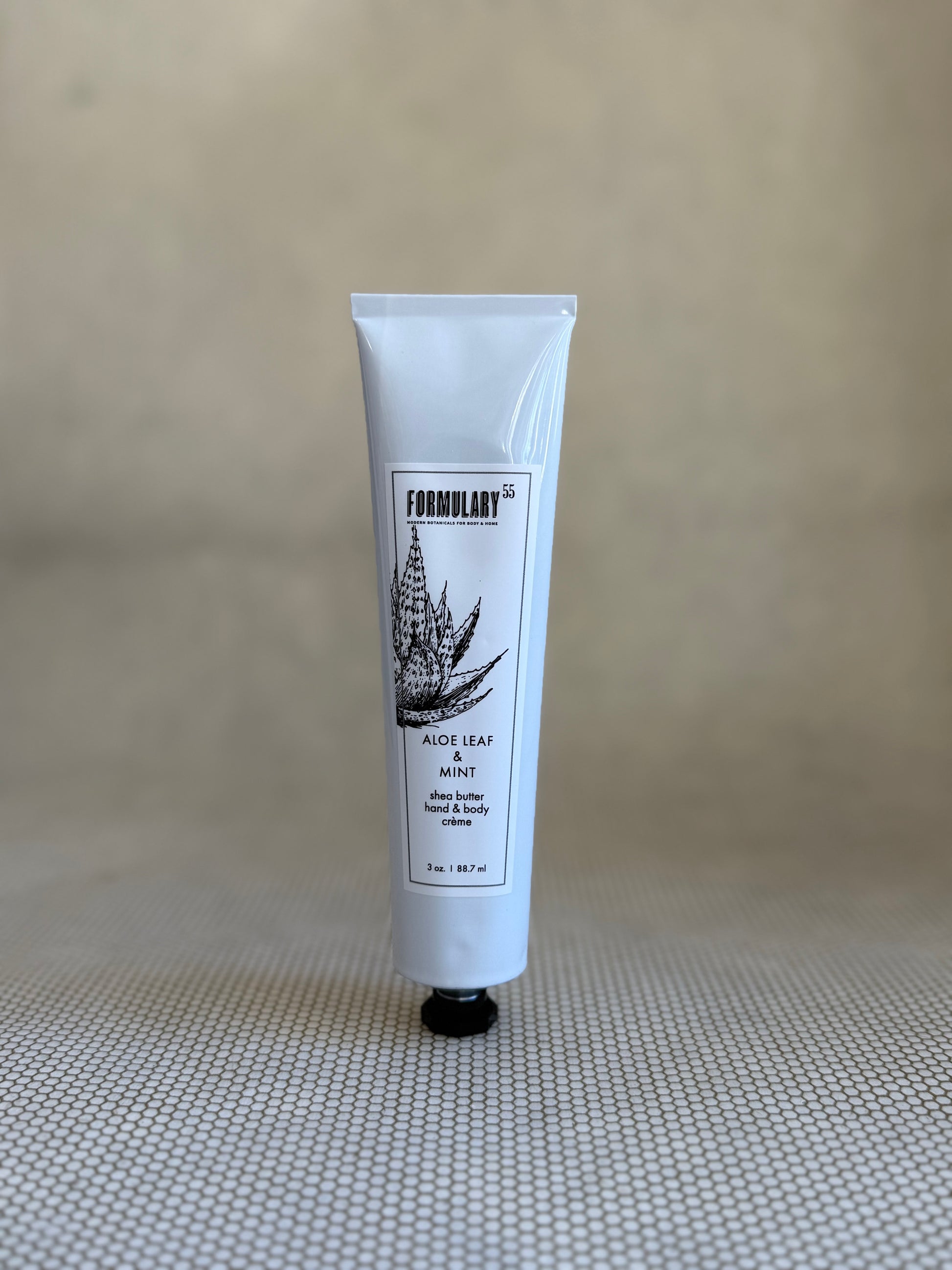 Tube of Formulary 55 aloe vera hand and body lotion on a neutral background