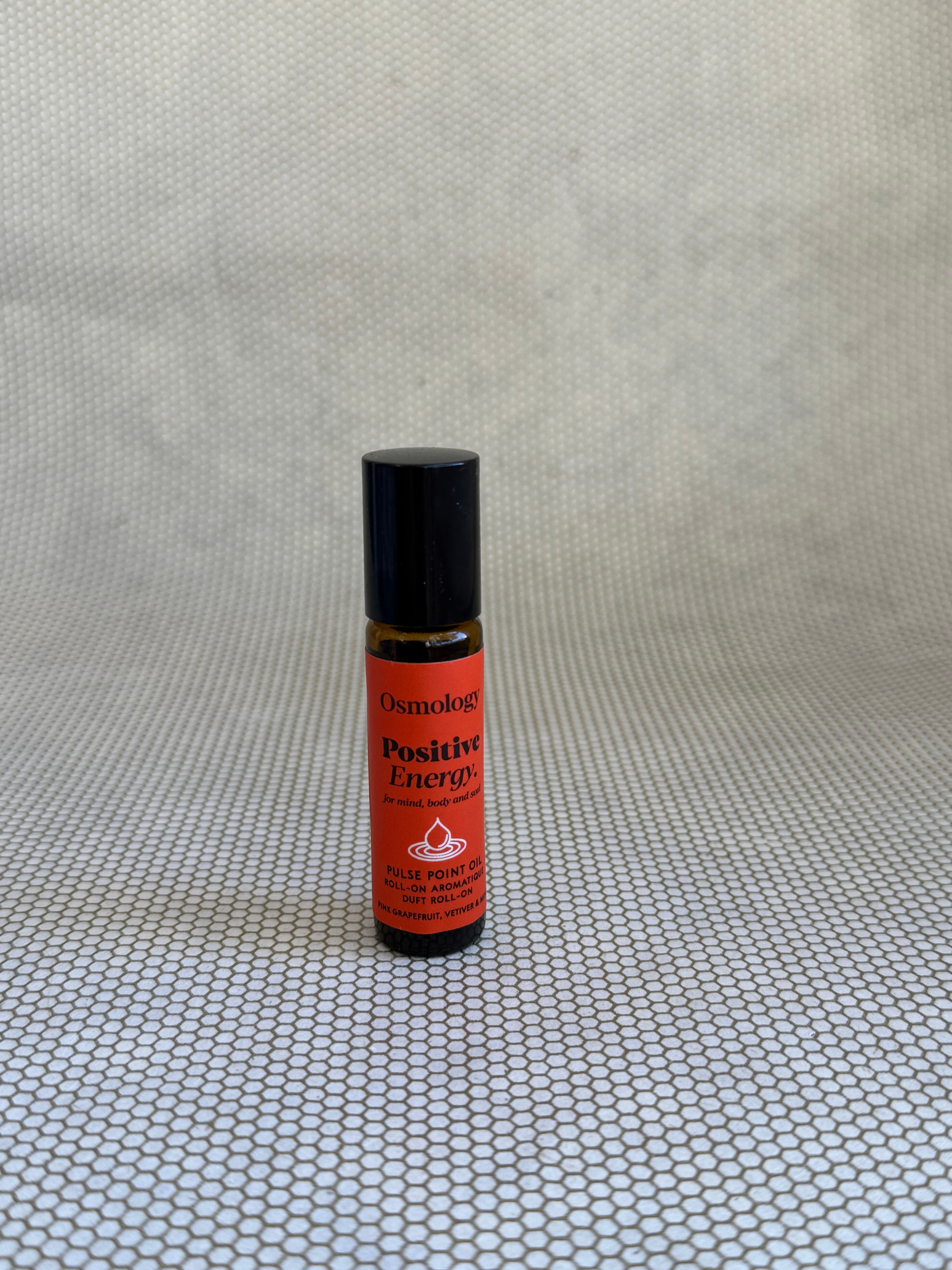 Osmology Positive Energy pulse point roll-on aromatherapy oil with red label and brown glass bottle.