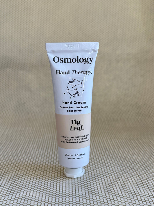Osmology Fig Leaf hand cream tube on a textured beige surface