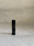 Black cylindrical Preston SPF Lip Balm on a textured beige surface