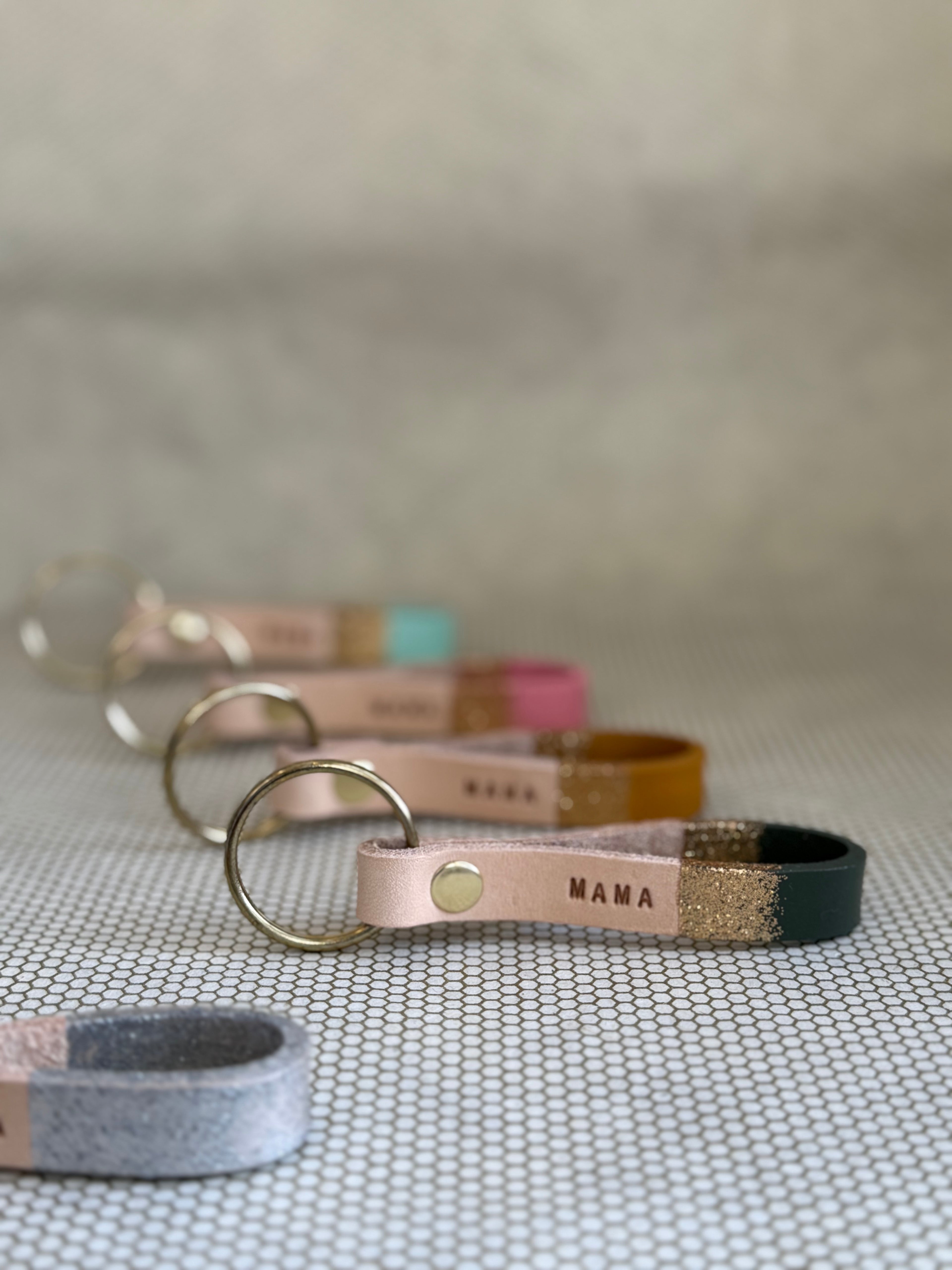 Set of varying color keychains with leather straps and "mama" lettering on leather. 