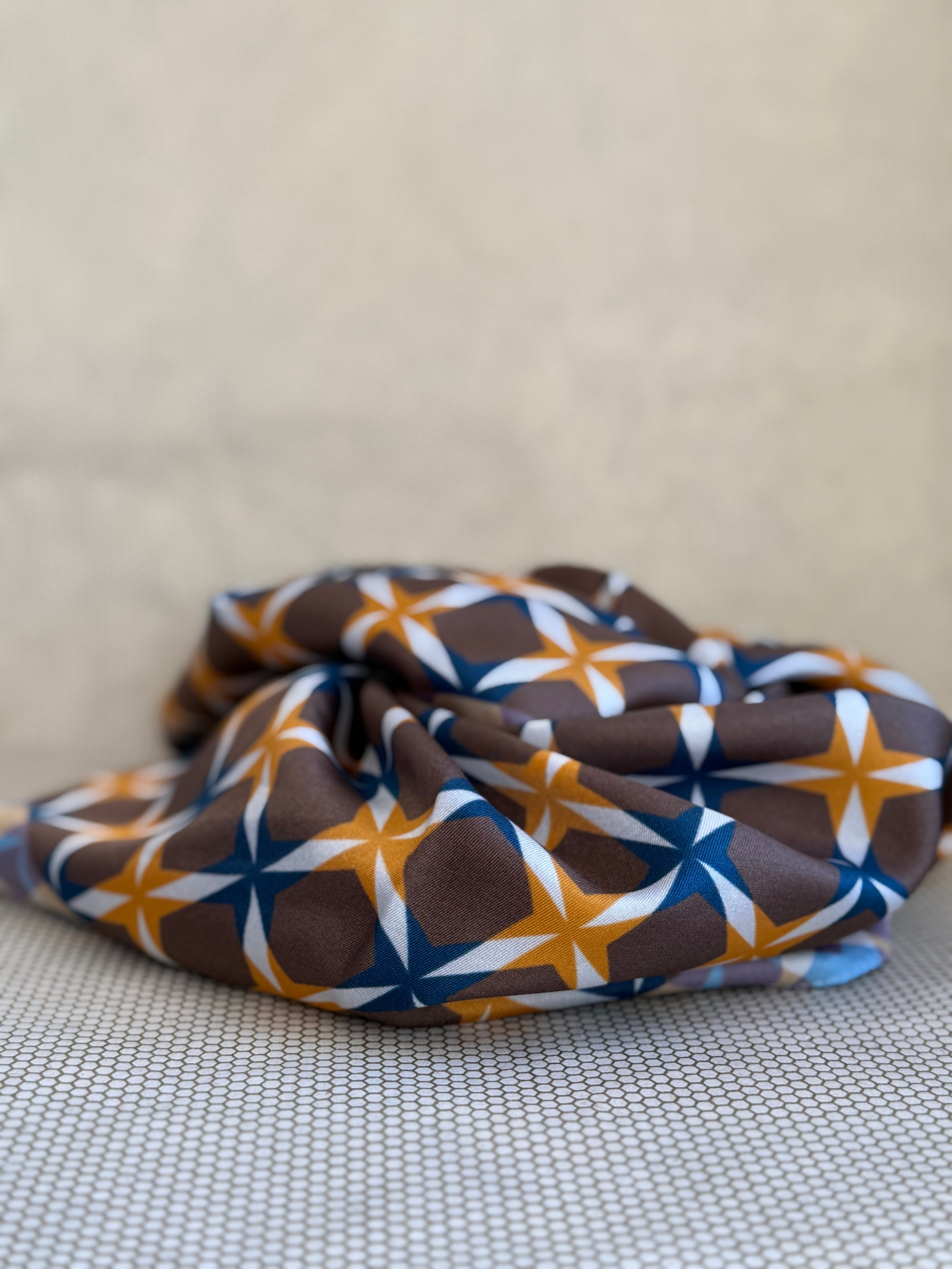 bunched silk scarf with geometric pattern on a textured surface