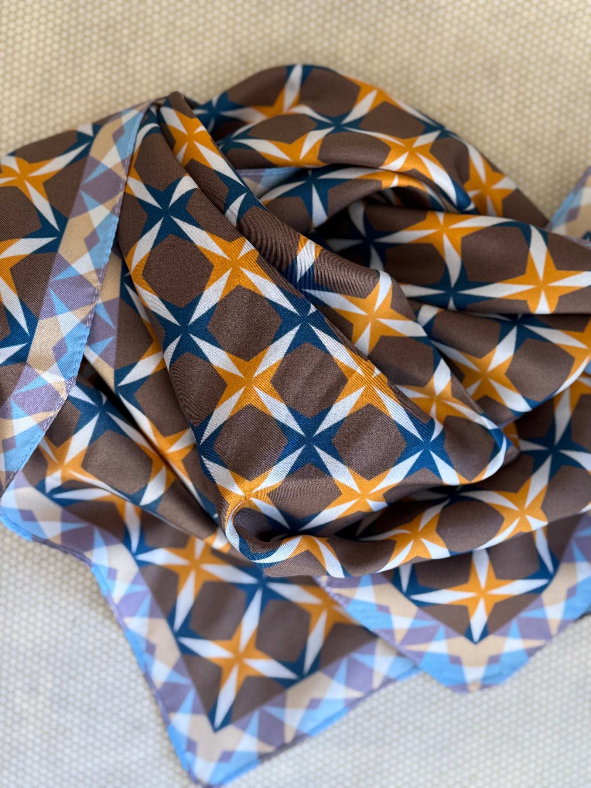 bunched silk scarf with geometric pattern on a textured surface