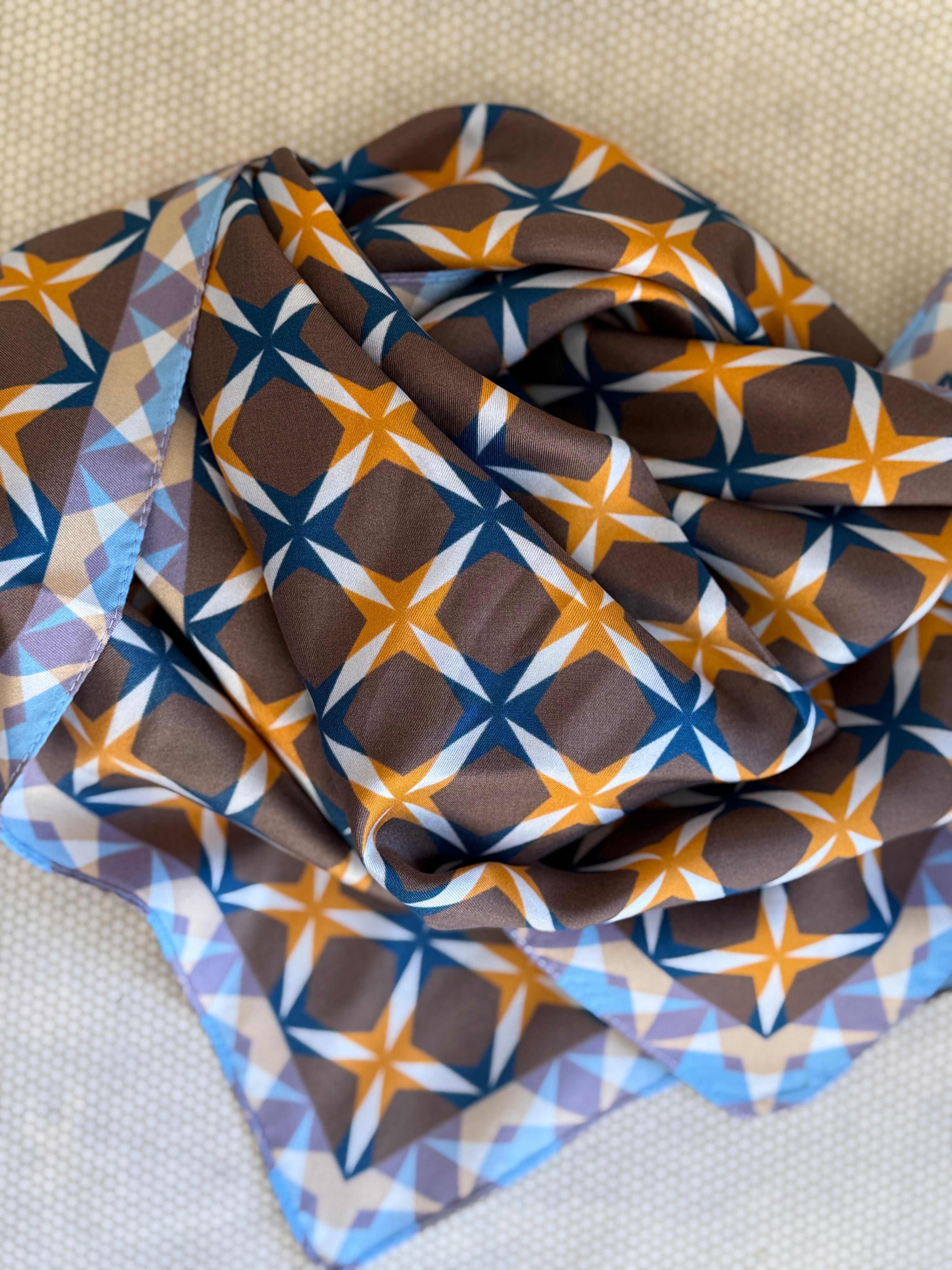 bunched silk scarf with geometric pattern on a textured surface